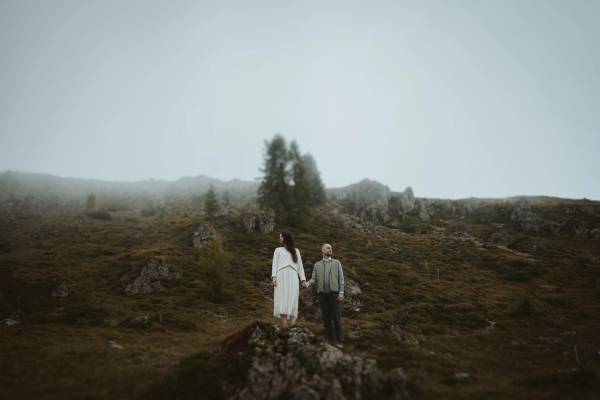 Jana and Steffen standing apart on a rock surrounded by pale mountain fog.