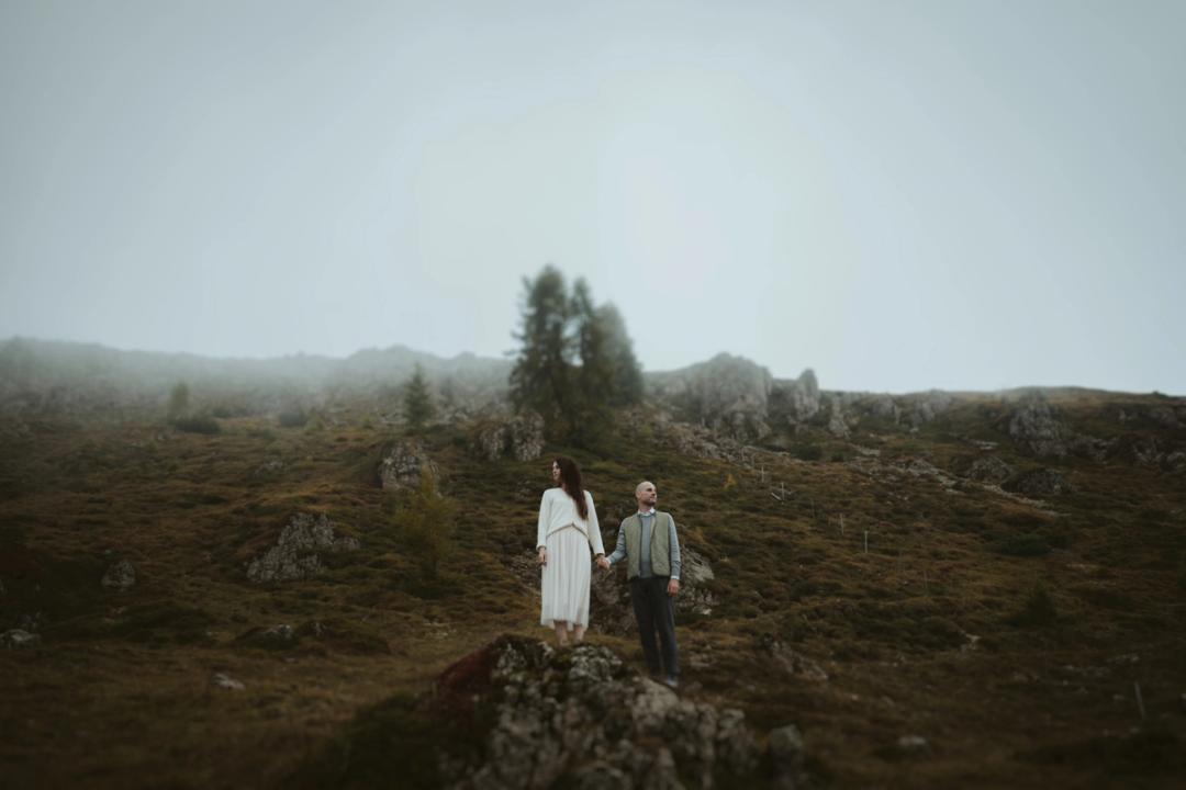 Jana und Steffen stehen mit etwas Abstand auf einem Fels im hellen Bergnebel.