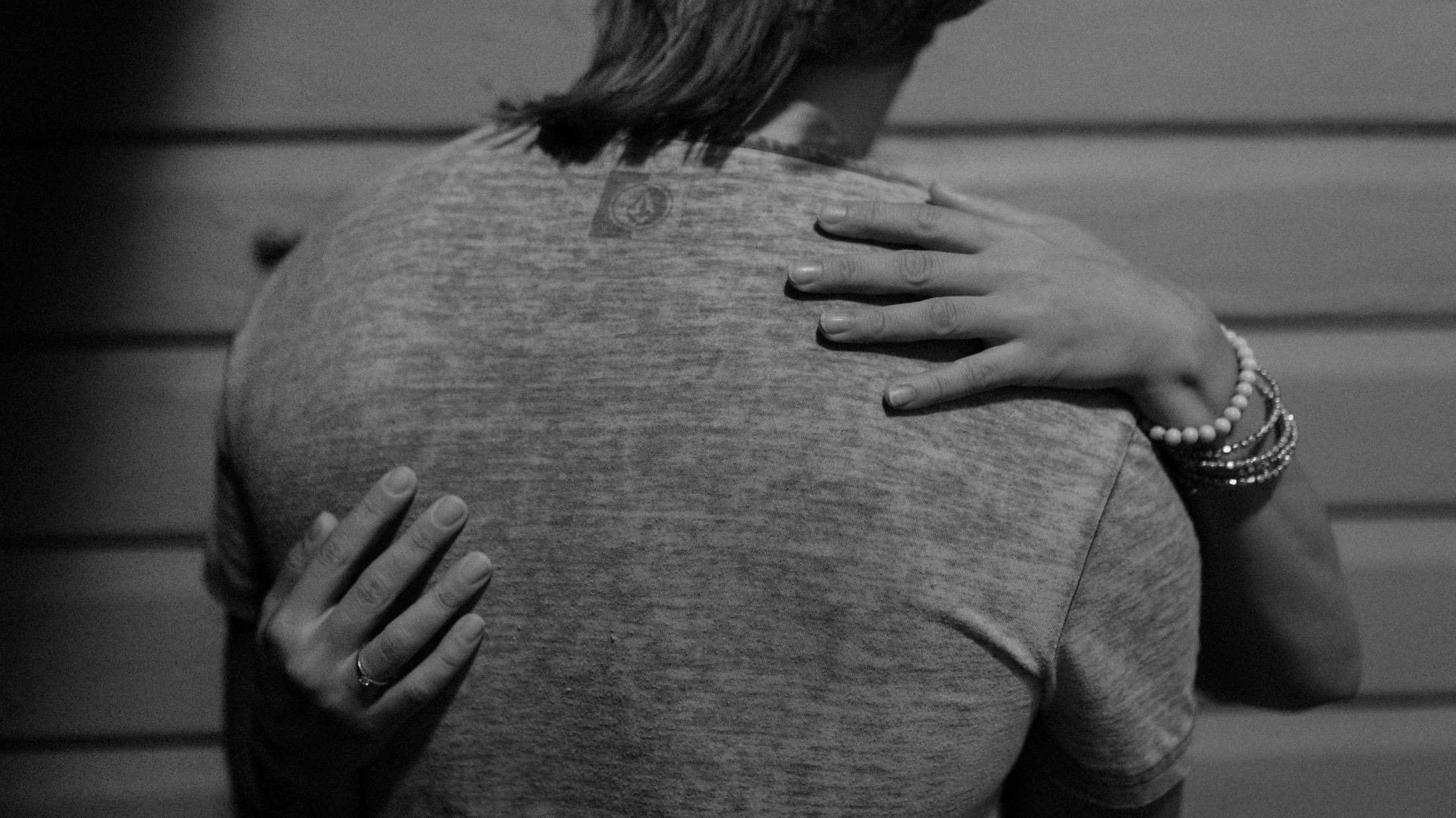 Black and white detail of Petra's hands resting on Roman's back