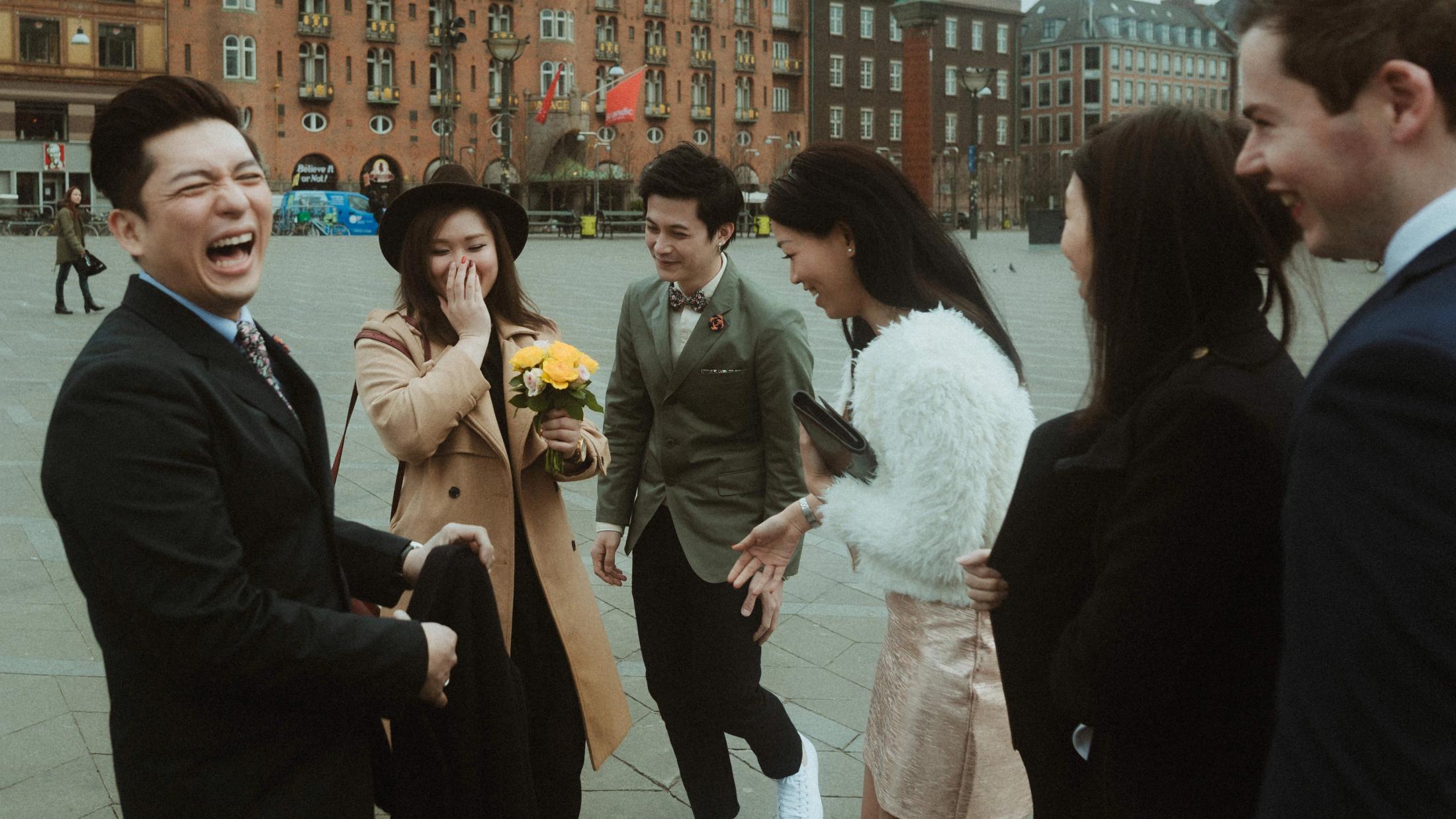 Kevin and Terence laugh with their friends outside Copenhagen City Hall.