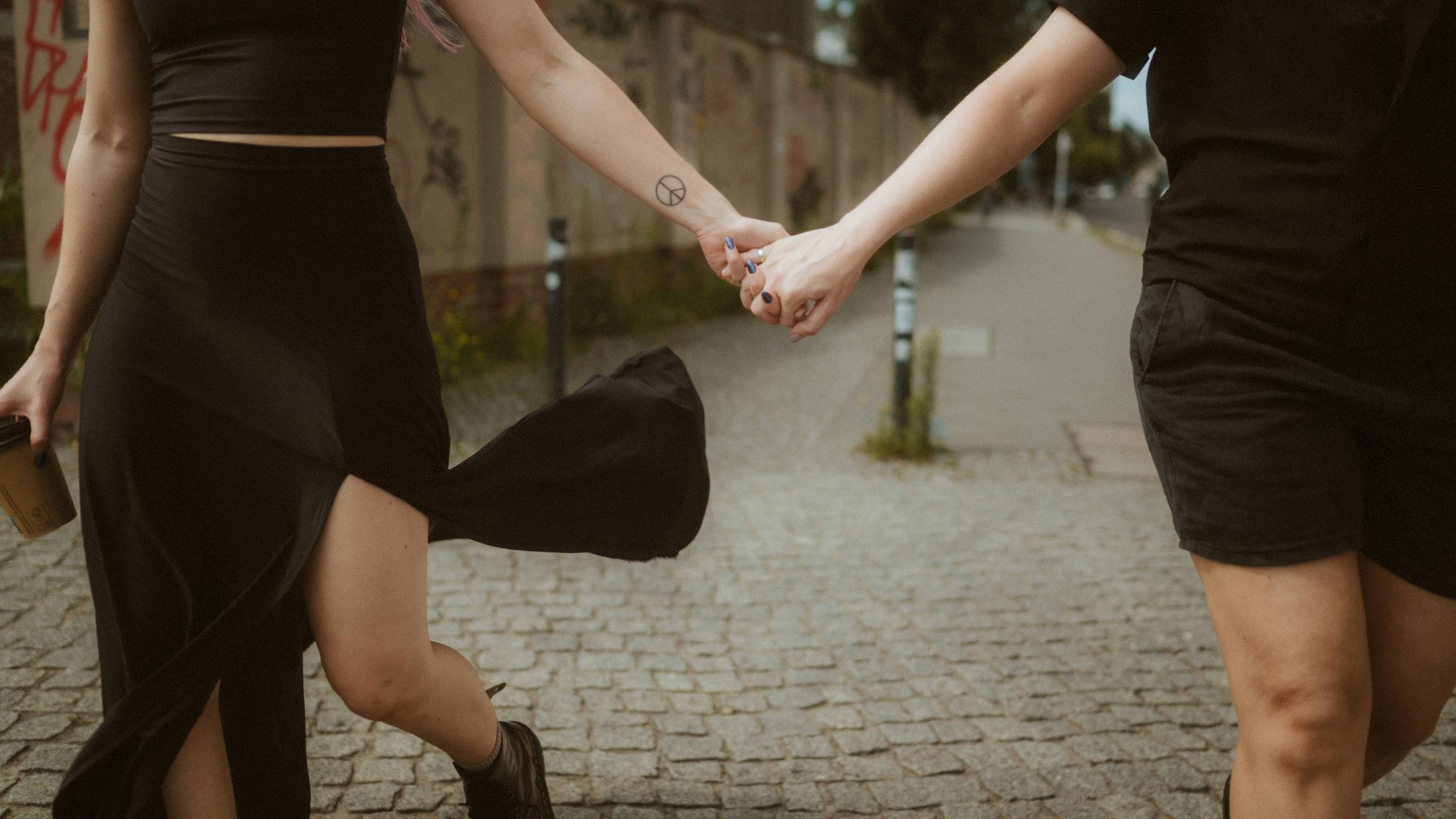 Close view of Noah and Michèle's joined hands as they run along the street.