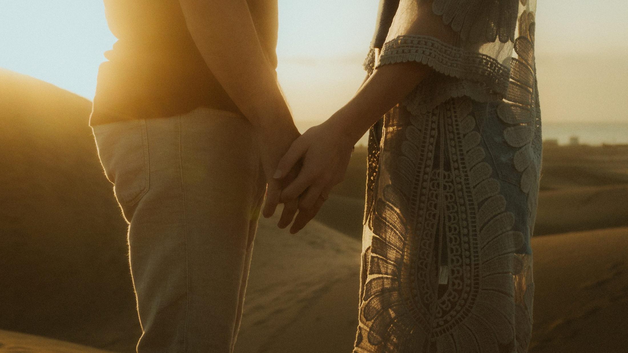 Katja and David's hands reaching toward each other in backlight.