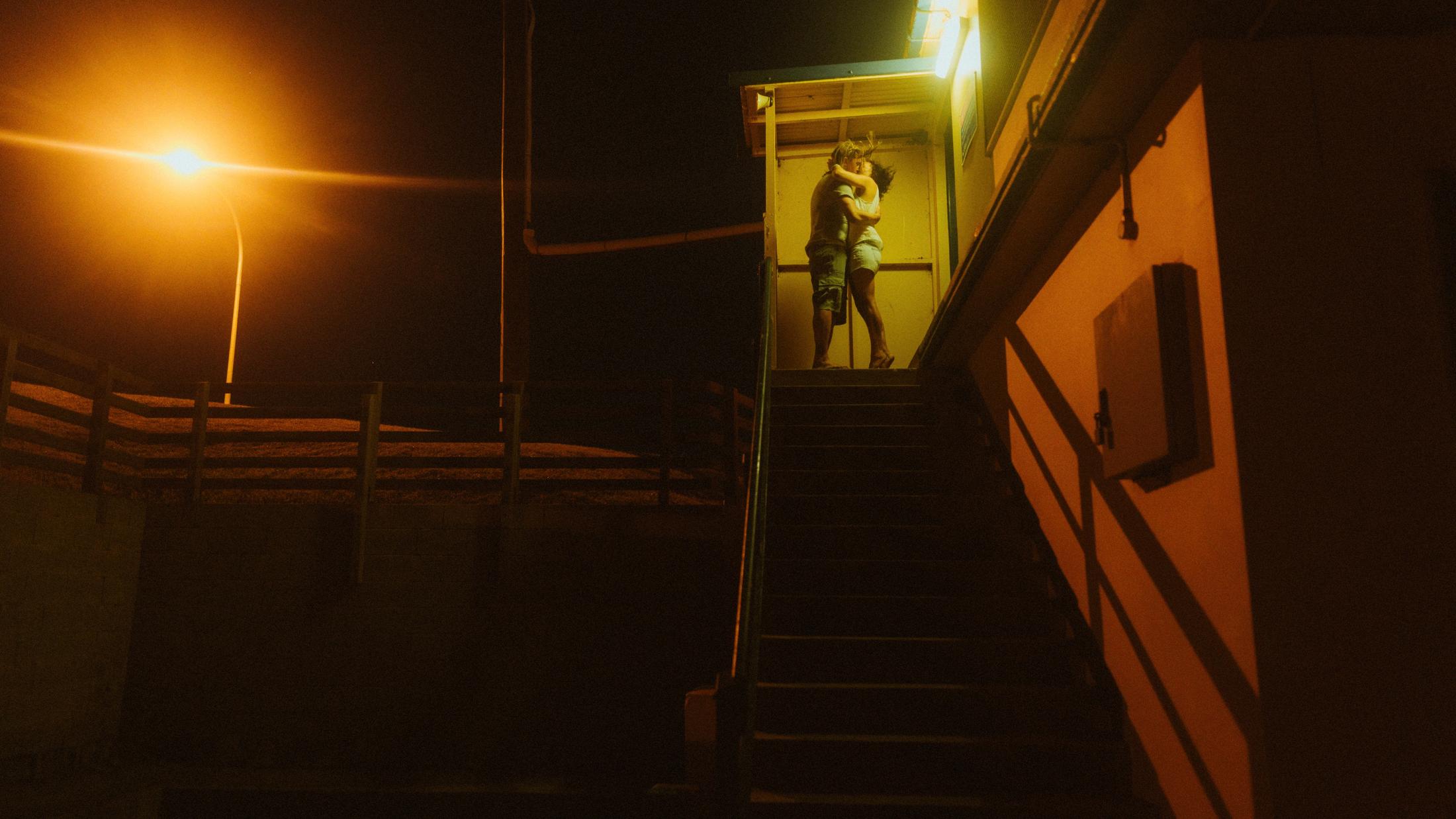 Petra and Roman standing small in the doorway of a lit beach building
