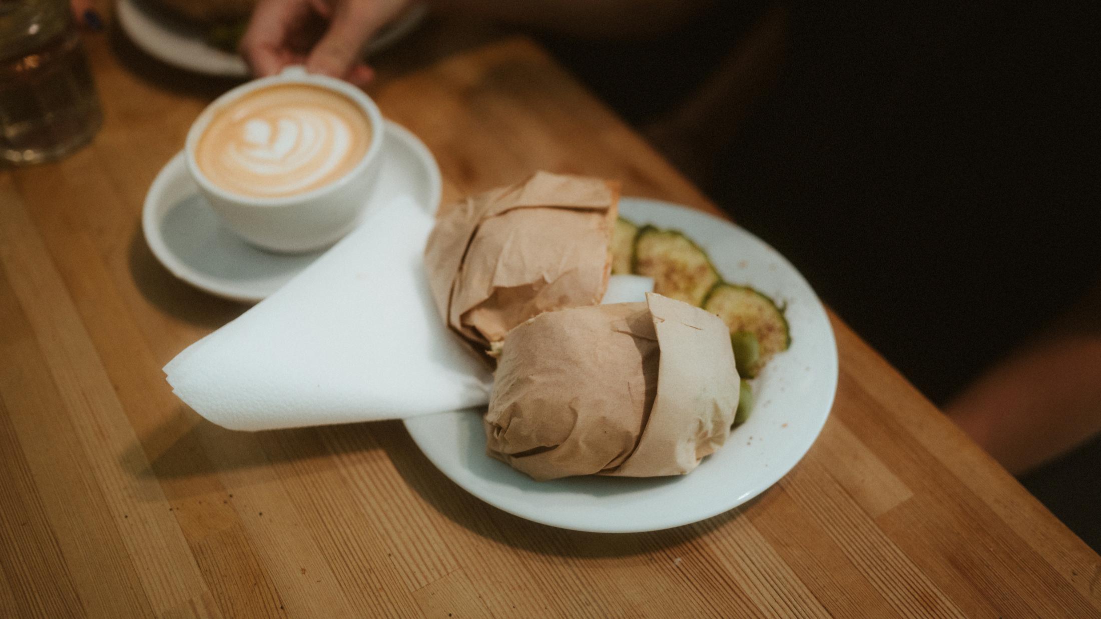 Coffee, food and a book arranged on a small café table.