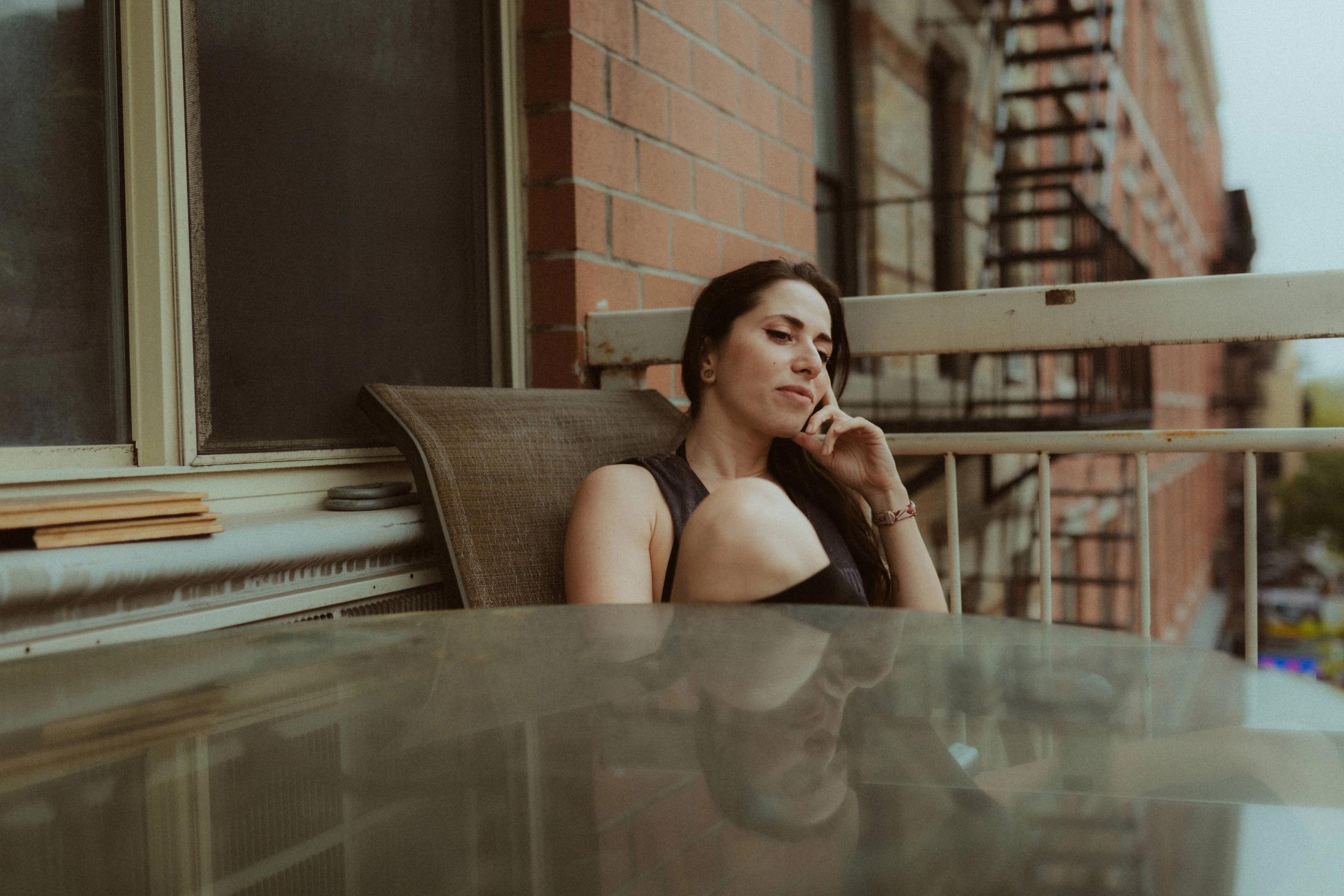 Maya sitting quietly on the balcony above a Manhattan street.