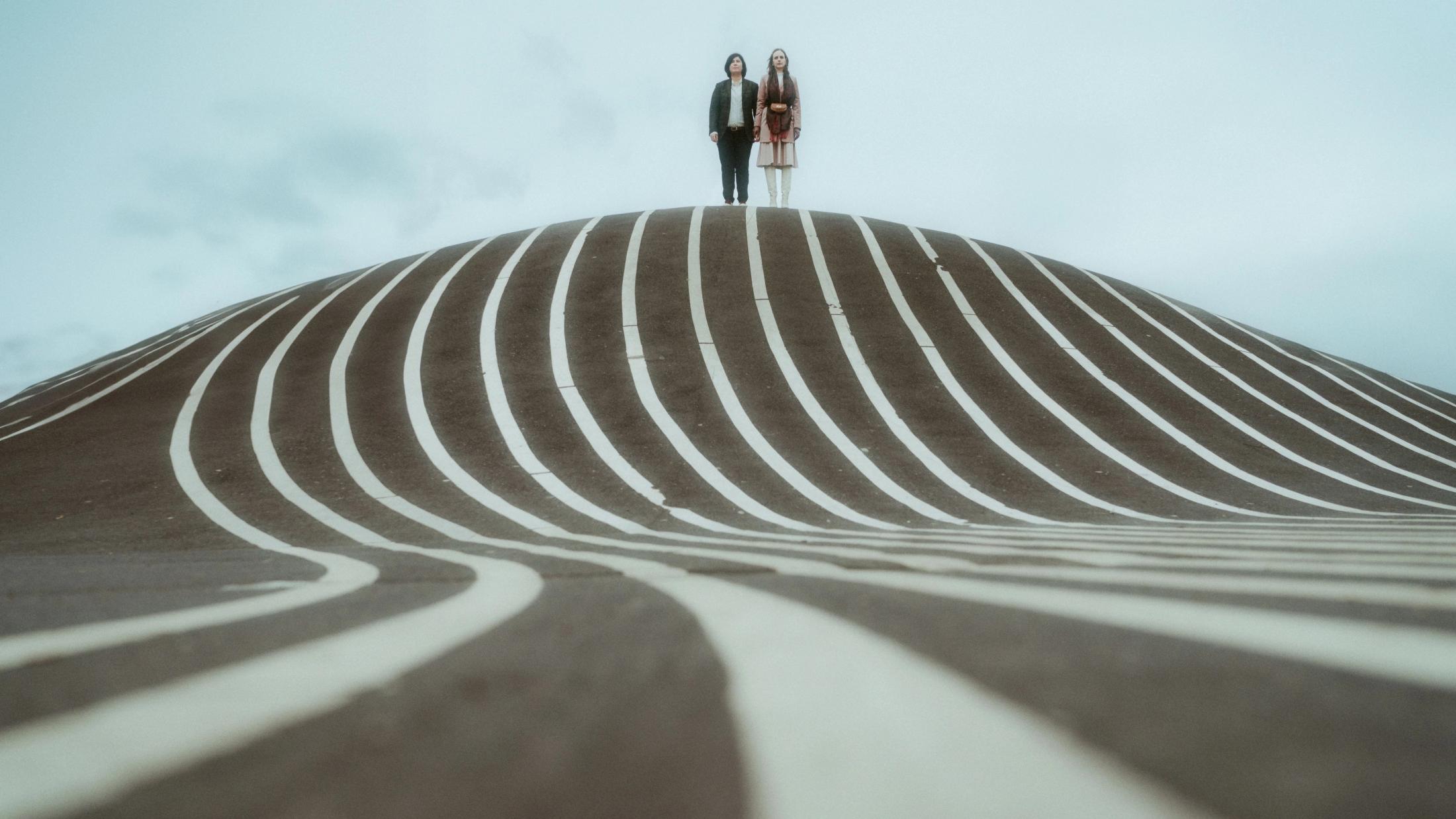 Ari and Pia appearing small on top of a striped hill