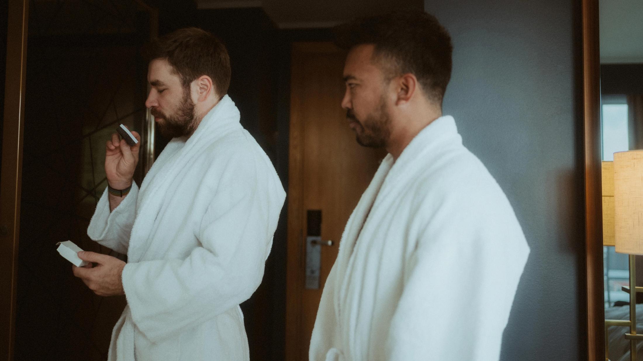 Kris and Ilya stand side by side in white hotel robes.