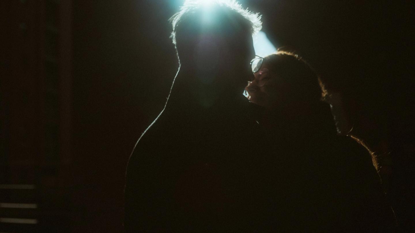 Nicole and Fritjof kiss as dark silhouettes against a bright rim of light.