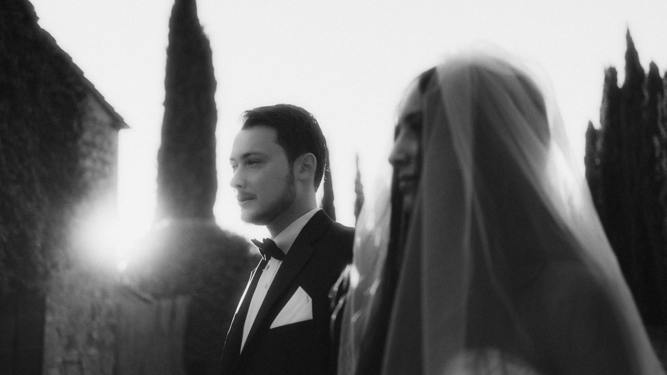 Black-and-white portrait of the couple standing side by side with sunlight between them.