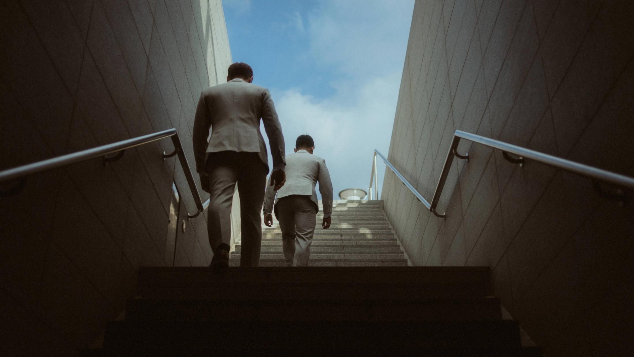Kris and Ilya walk upward through a concrete stairway between tall walls.
