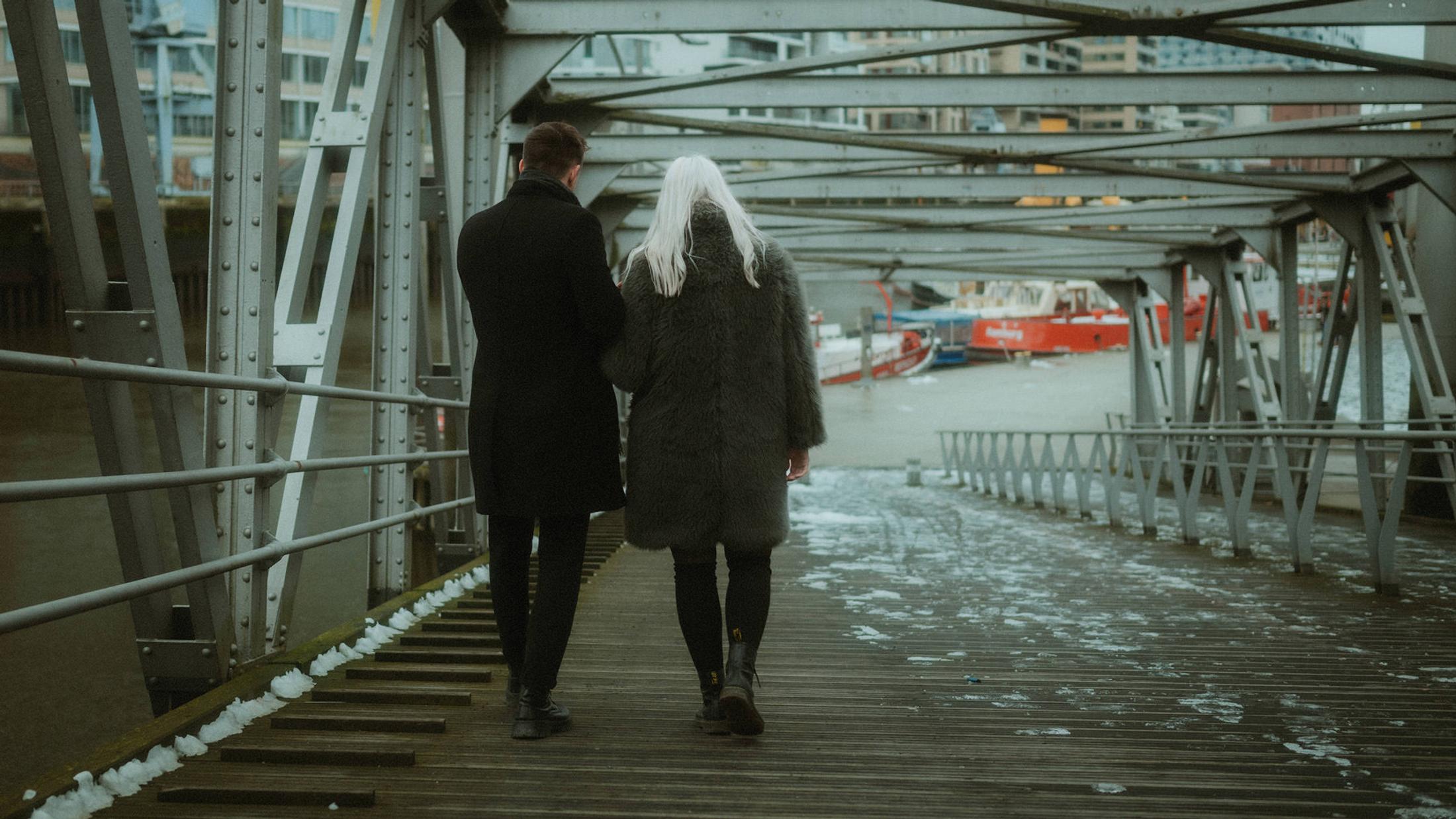 Lorelai and Steffen walk away together across a steel bridge in HafenCity.