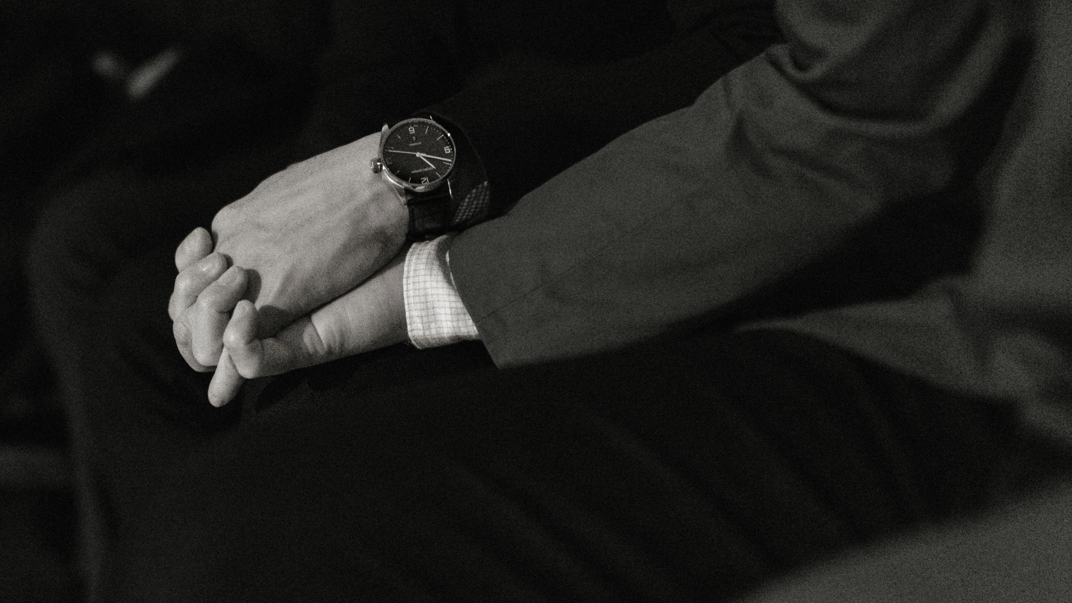 A close view of clasped hands resting in a groom’s lap before the ceremony.