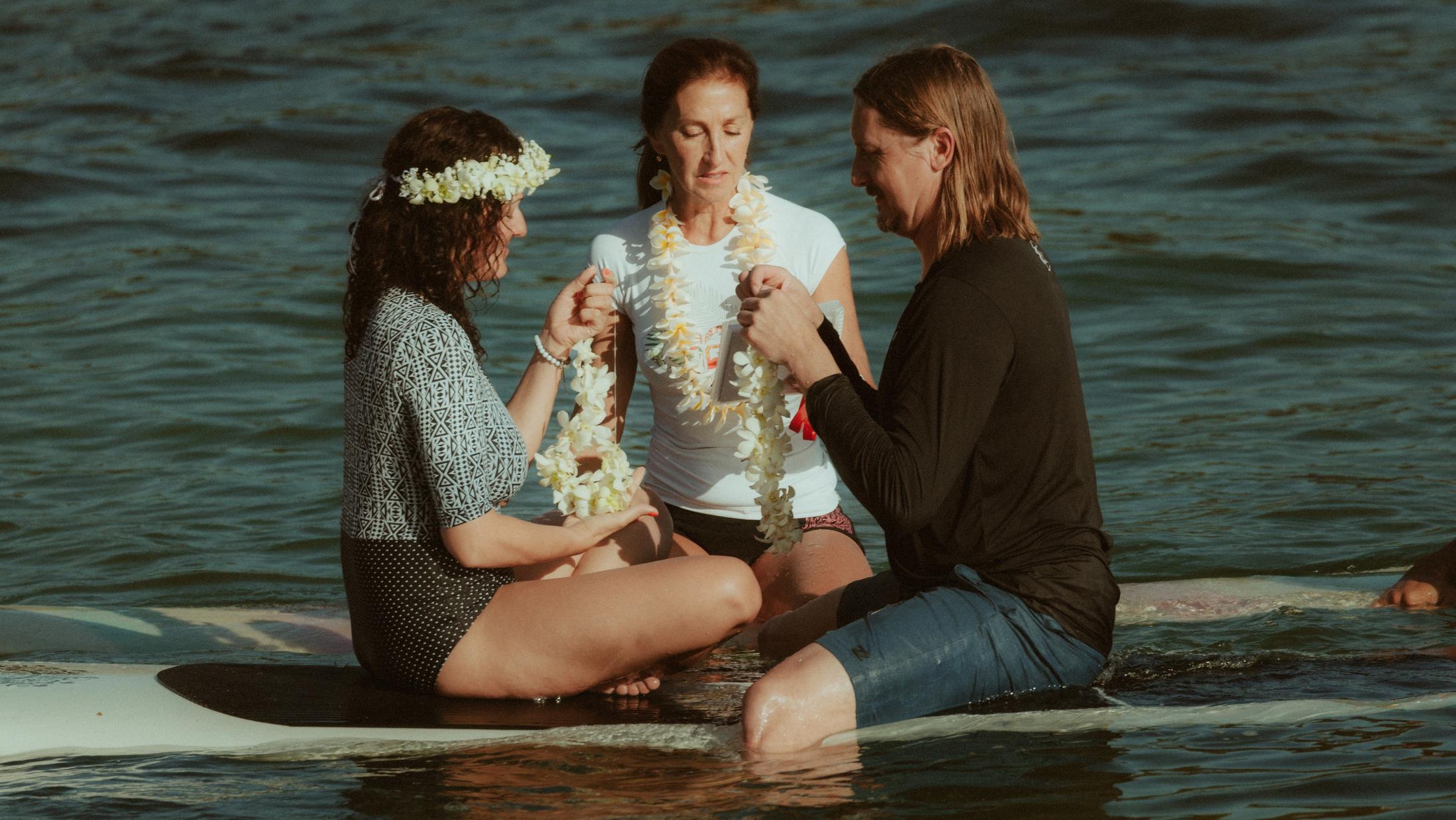 Petra and Roman exchanging vows on surfboards with the celebrant between them