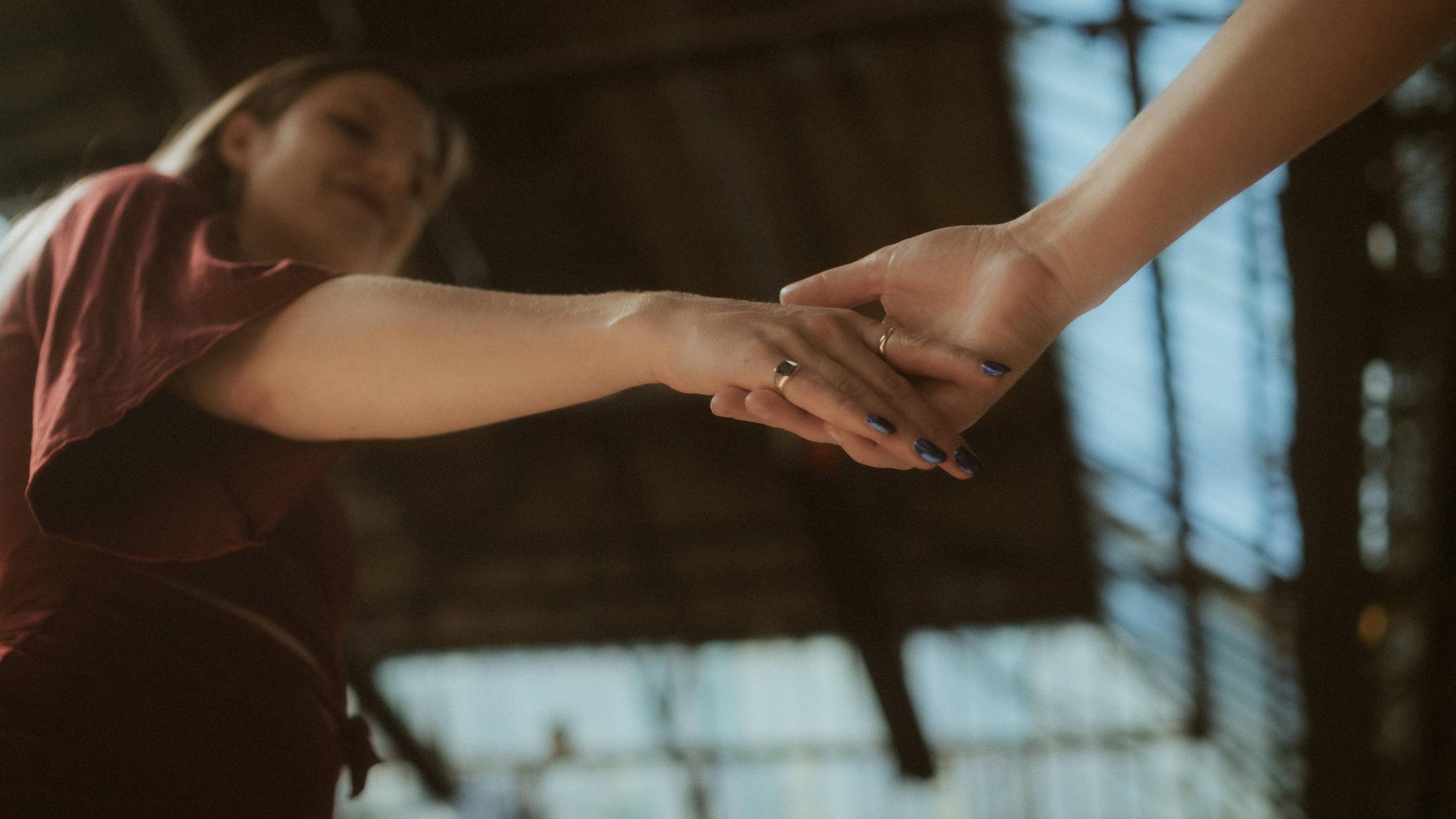 Noah and Michèle reaching toward each other with their fingertips nearly touching.