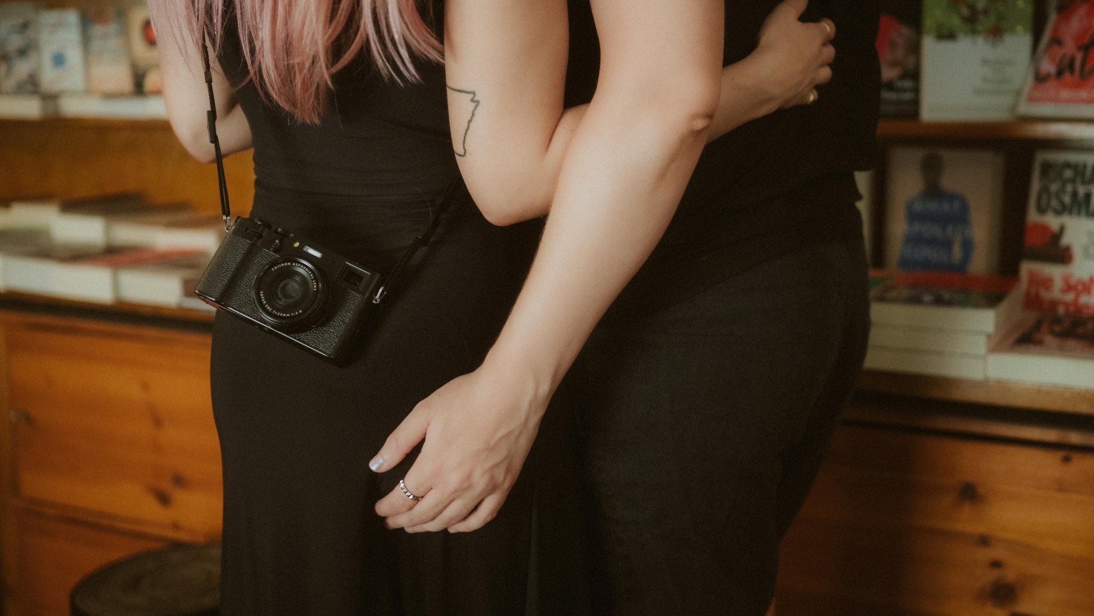 Michèle's camera hanging at her side as Noah rests a hand at her waist.