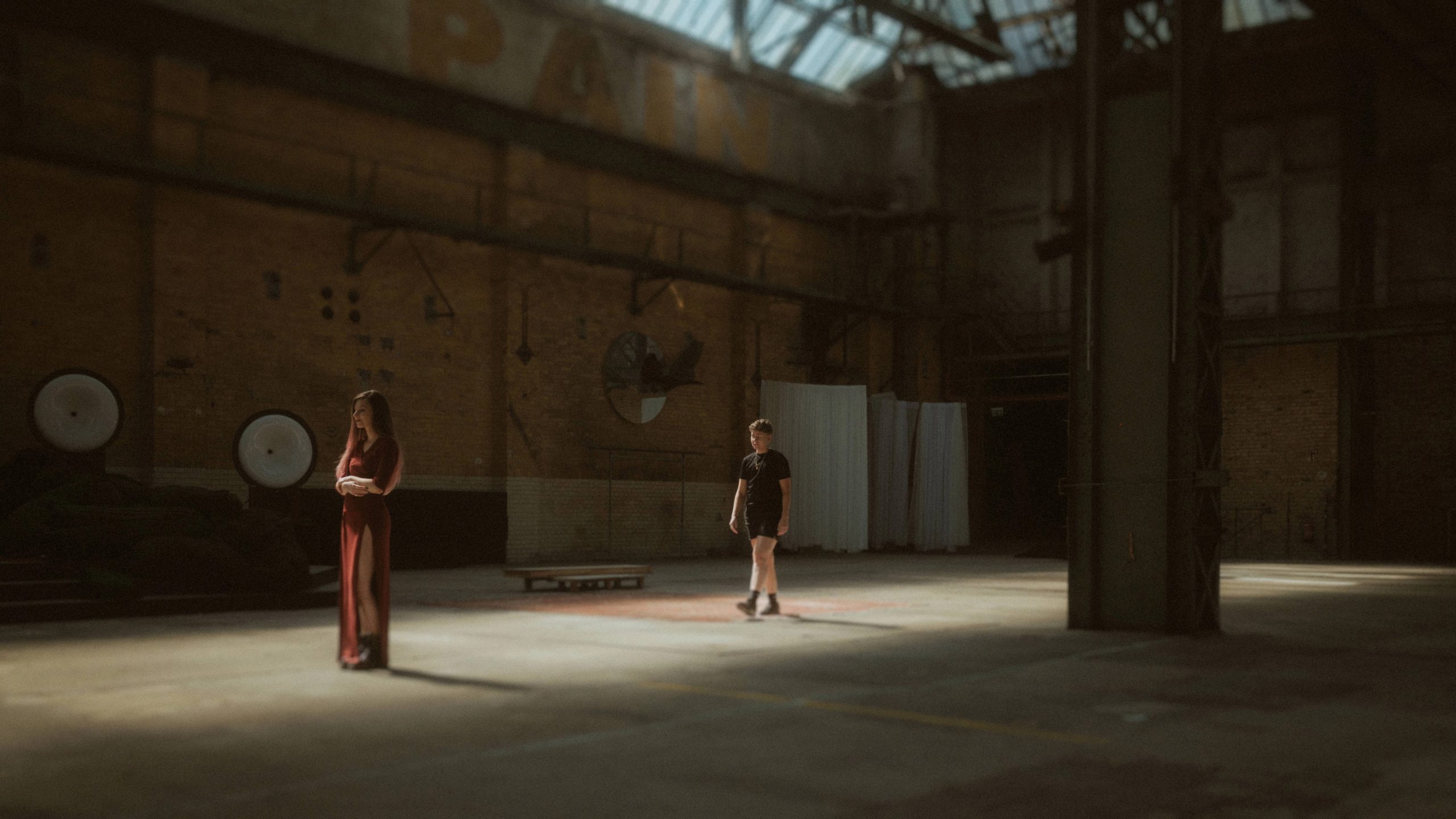 Noah and Michéle standing together in the vast light of an industrial hall