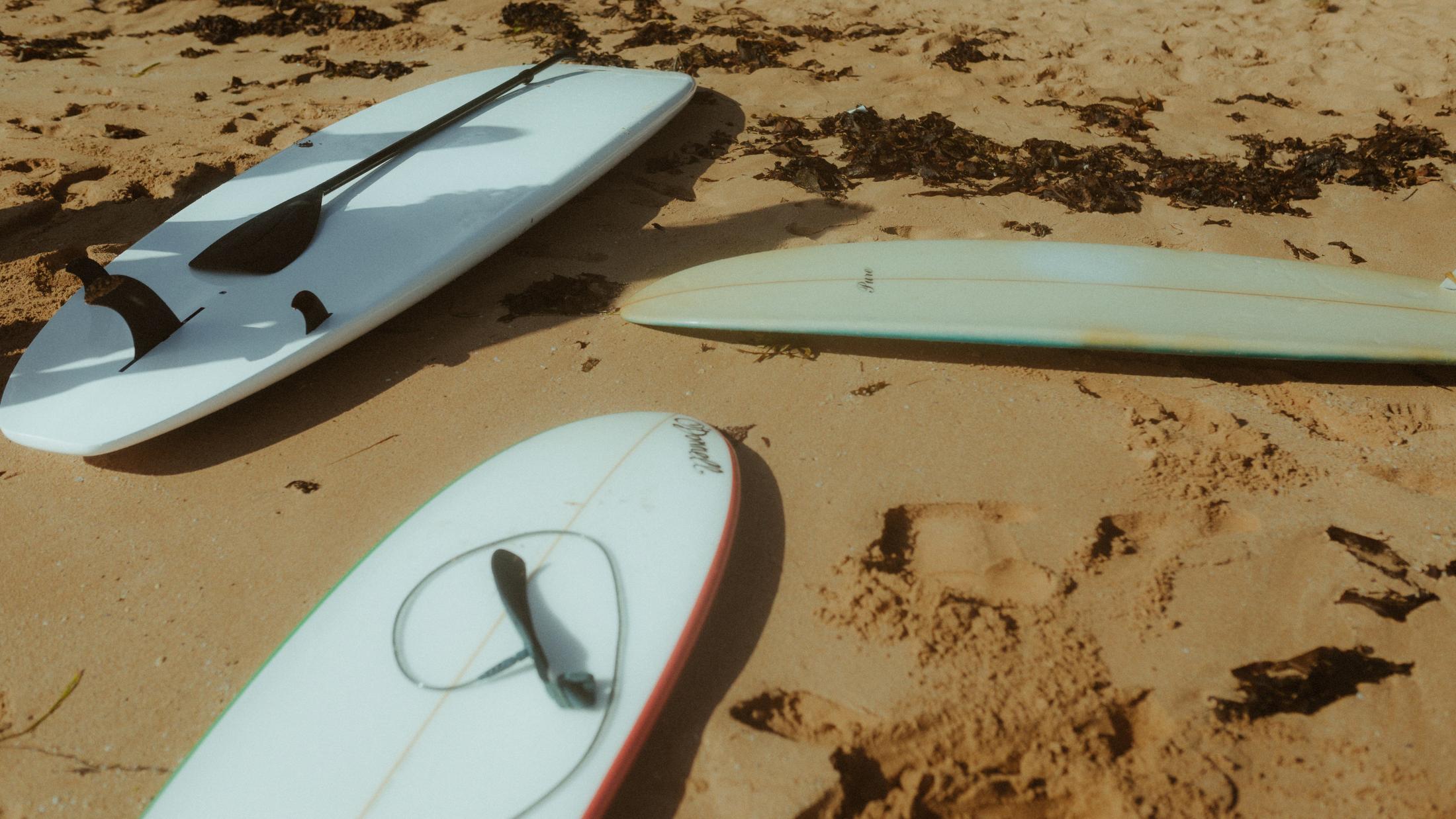 Three surfboards lying together on the sand
