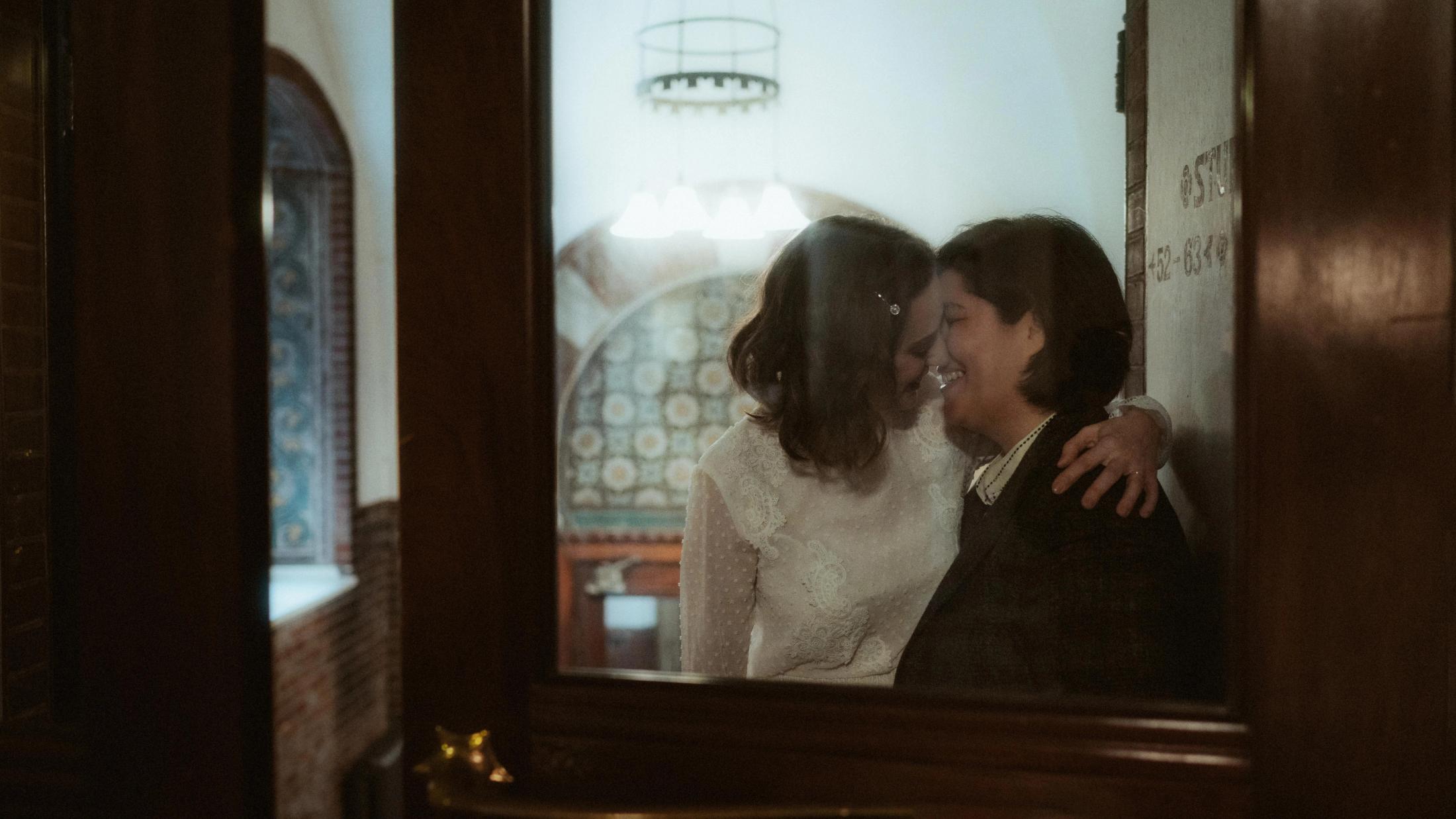 Ari and Pia kissing in a glass reflection