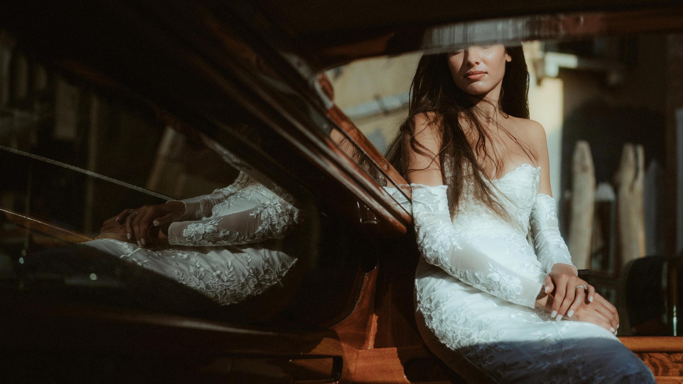 The bride sits inside a wooden boat, framed by a dark reflection across the image.