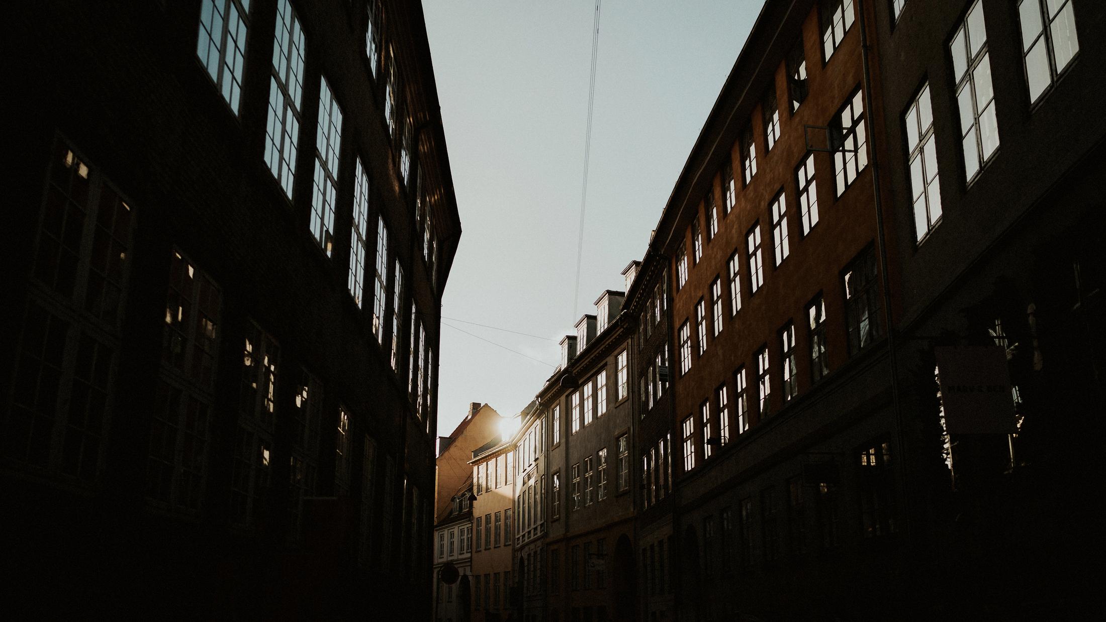 Low sunlight falls between tall Copenhagen facades.