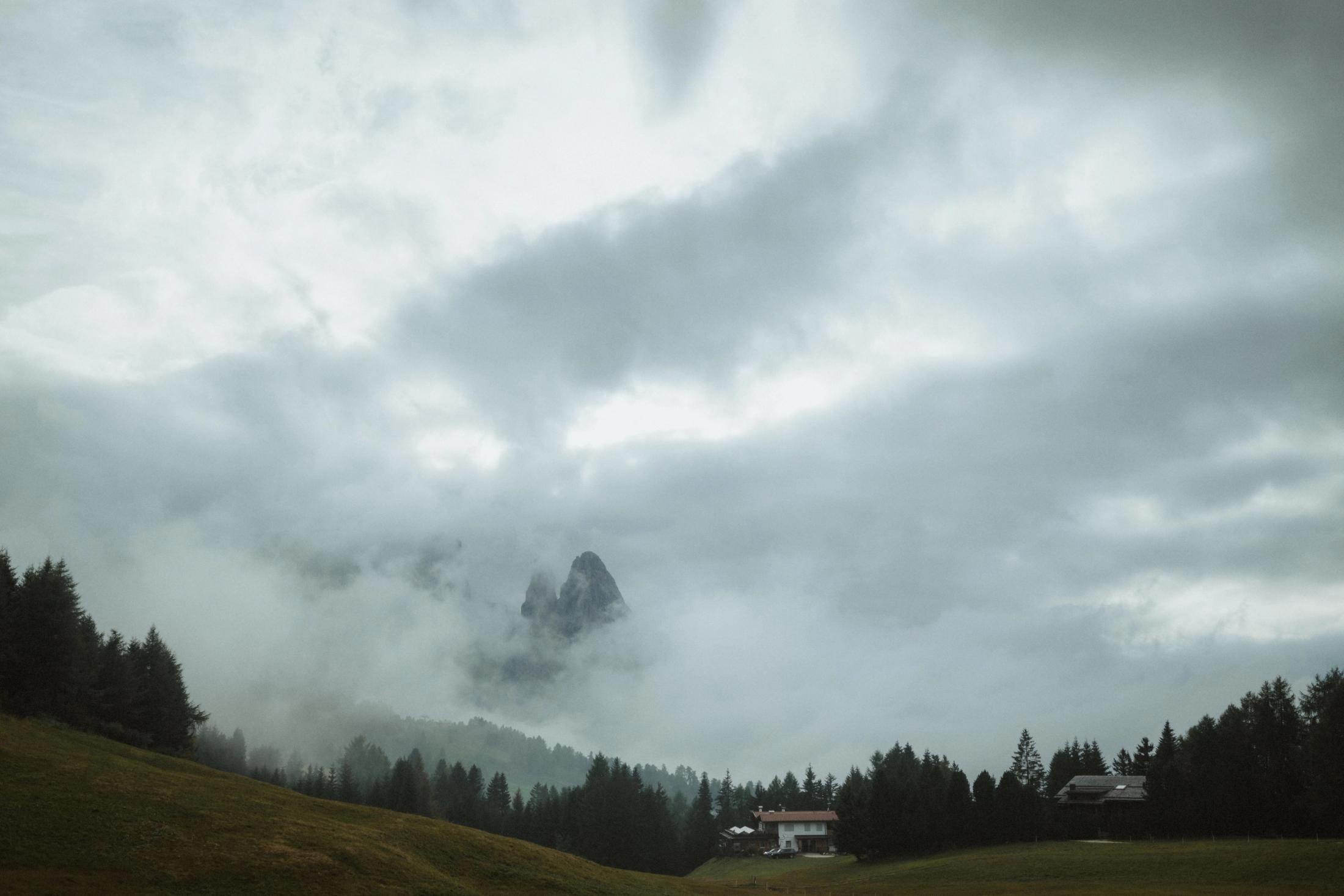 A jagged Dolomite peak partly hidden by closing cloud.