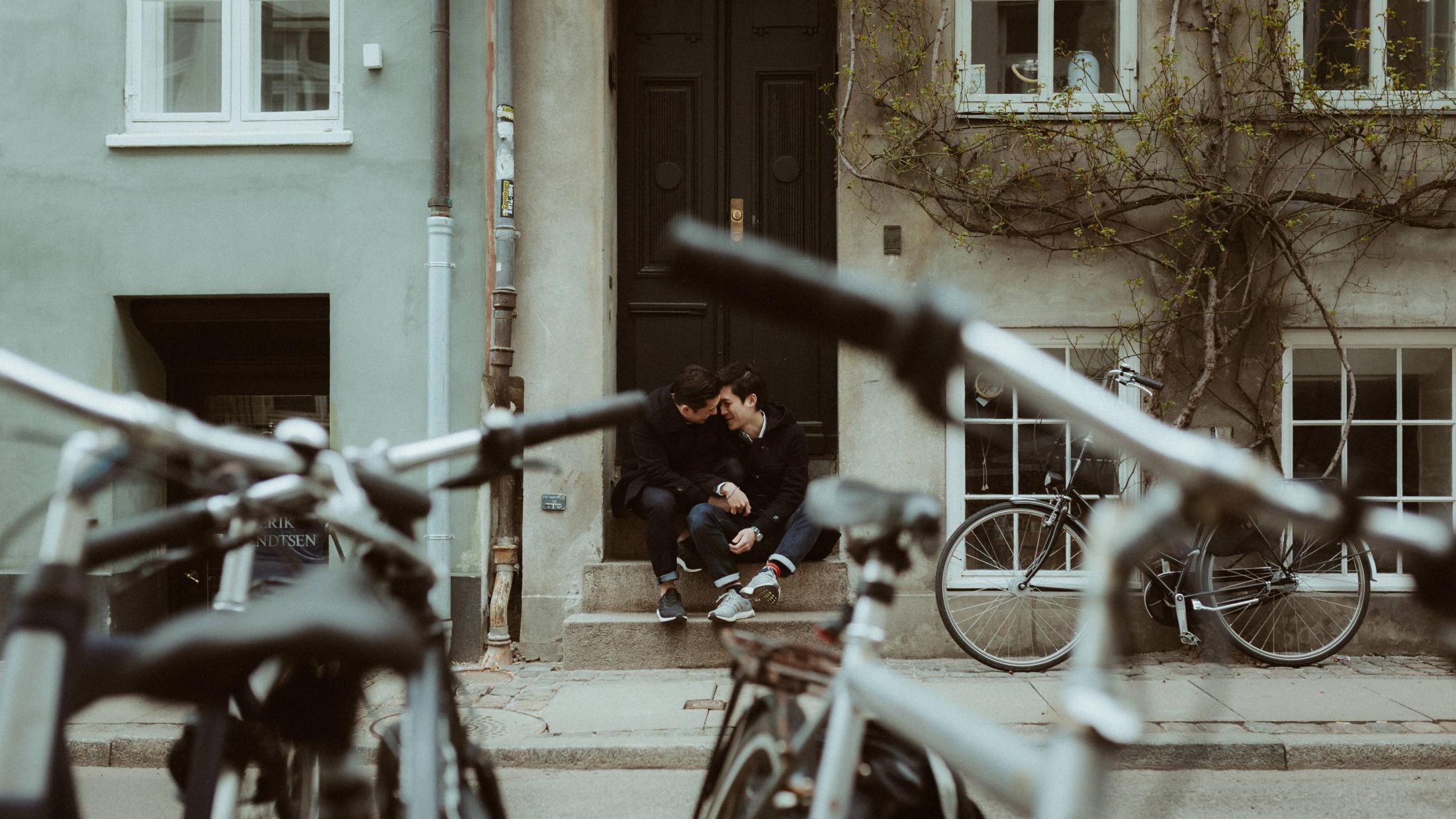 Kevin and Terence sit on a doorstep behind a row of bicycles.