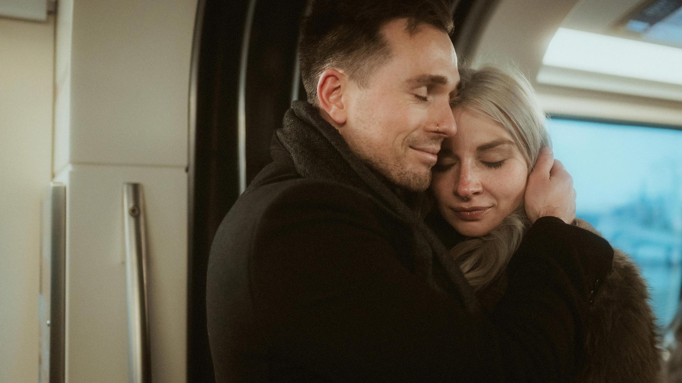 Steffen holds Lorelai closely inside the U-Bahn, both with closed eyes.