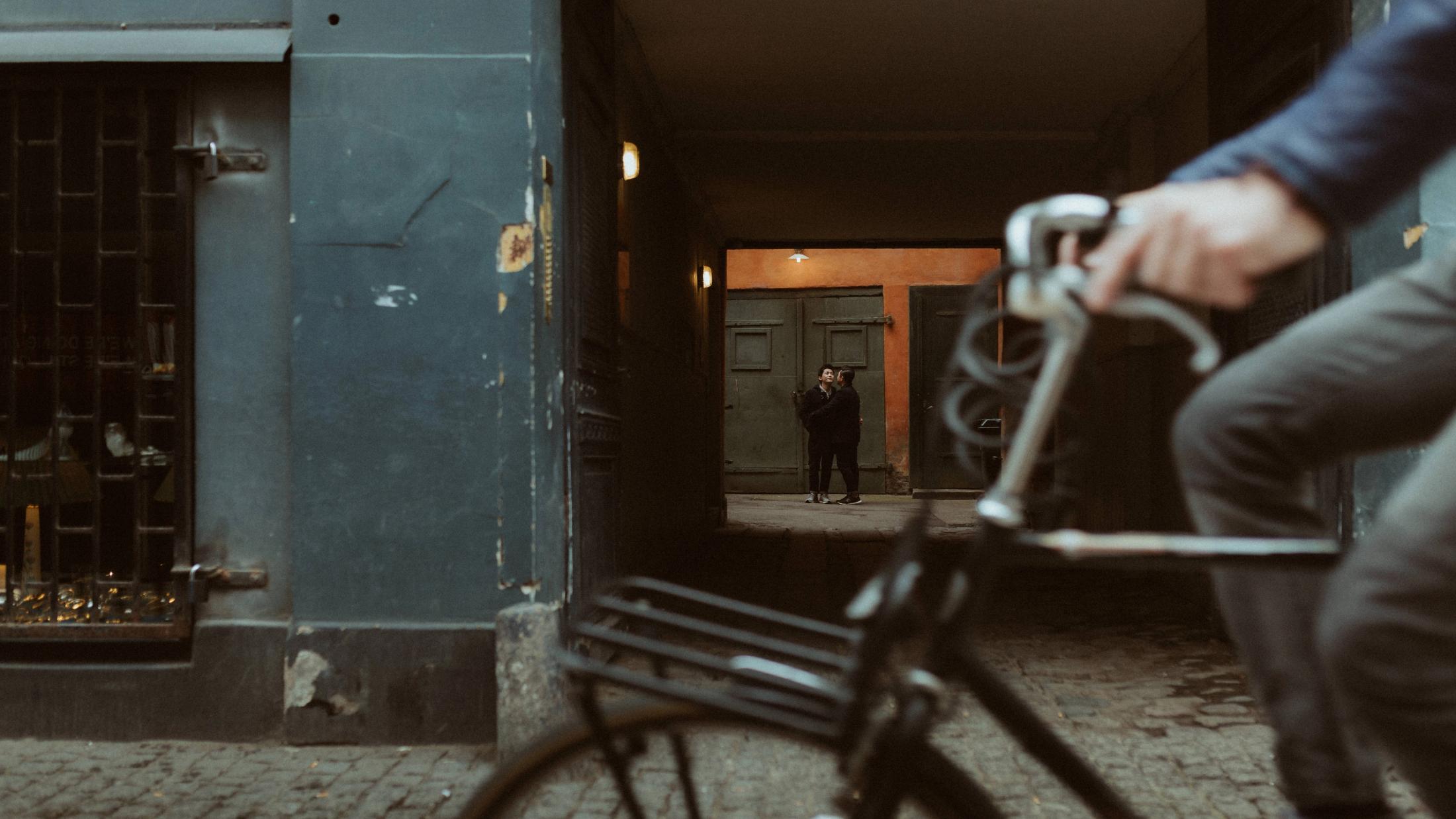 A cyclist passes through the foreground of a Copenhagen street during the portrait session.