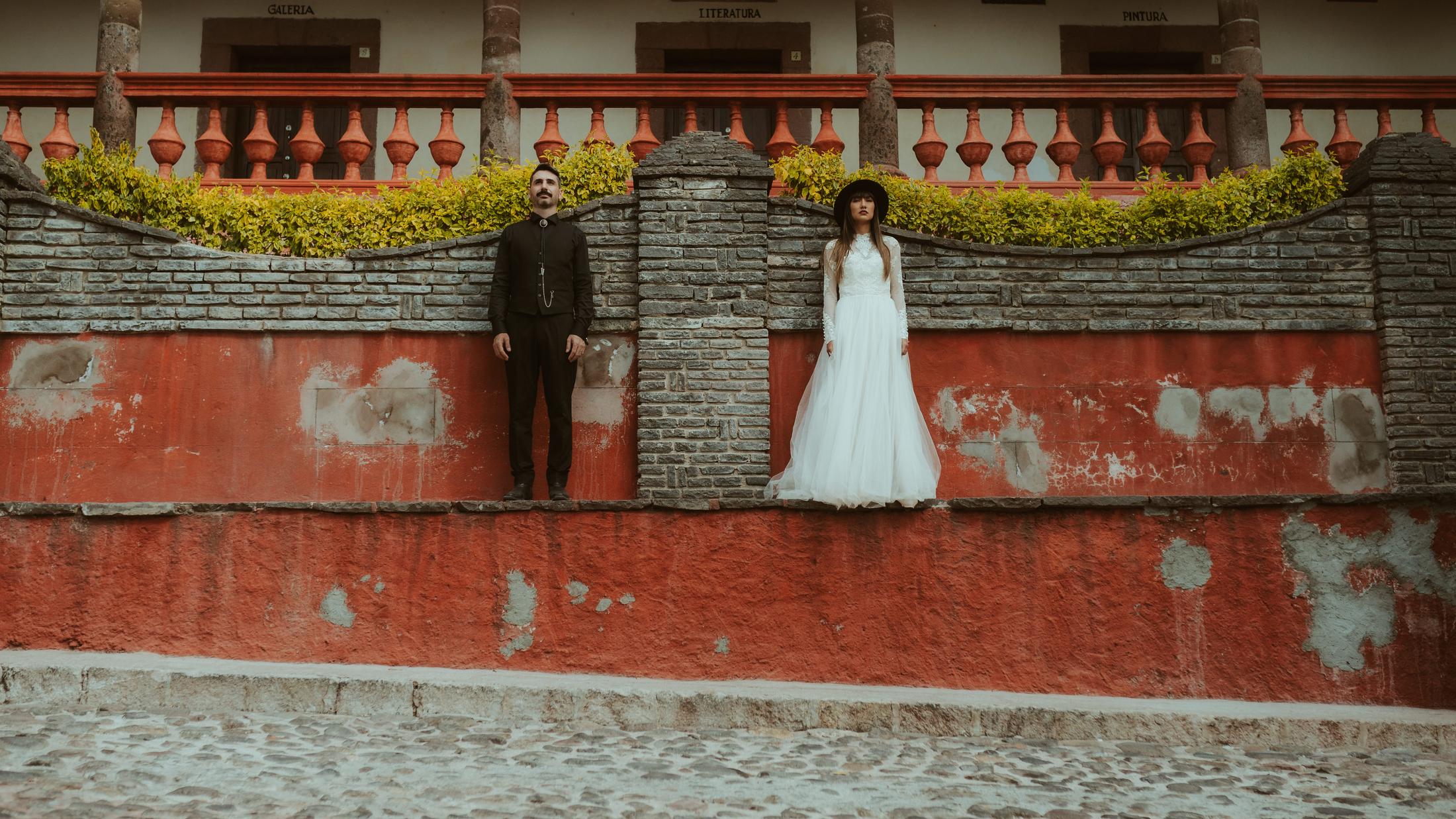 Das Paar steht in einem roten Innenhof in San Miguel de Allende.