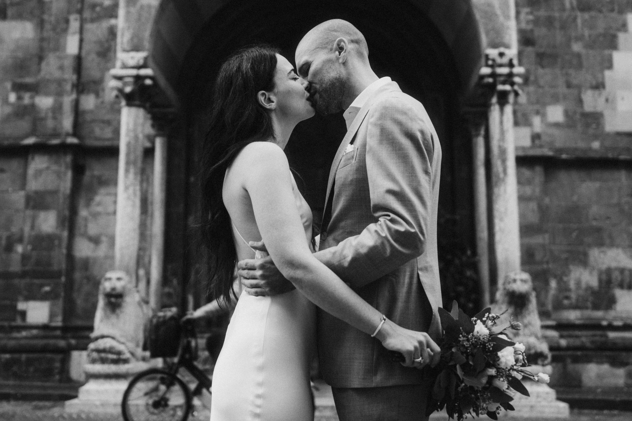 Jana and Steffen kissing outside a church as a bicycle crosses the foreground.