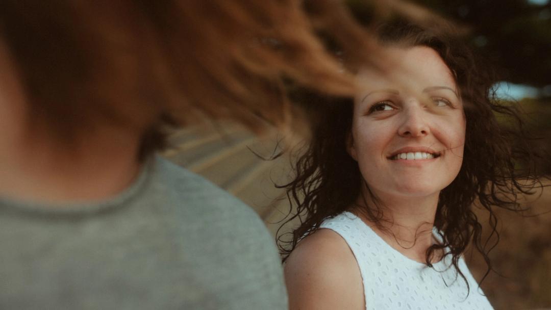 Petra smiling up at Roman beside the beach