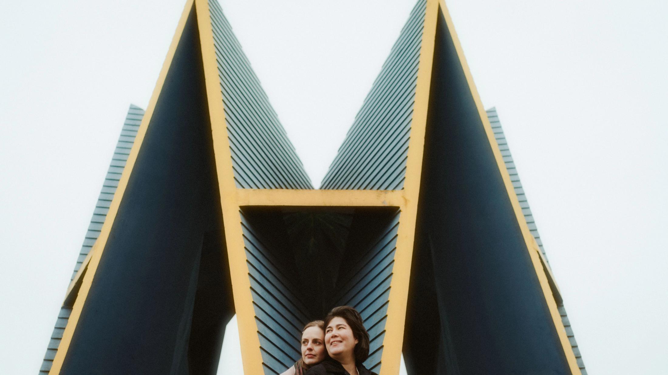 Ari and Pia standing beneath an angular modern building