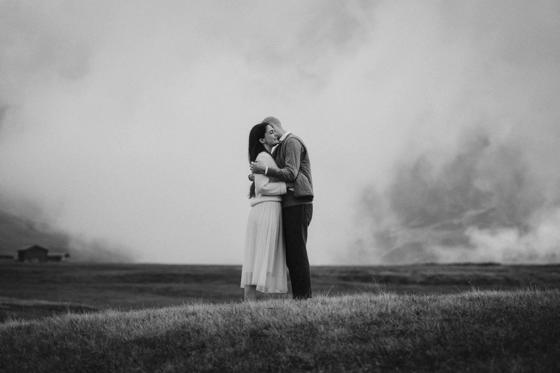 Black-and-white view of Jana and Steffen embracing beneath the clouds.
