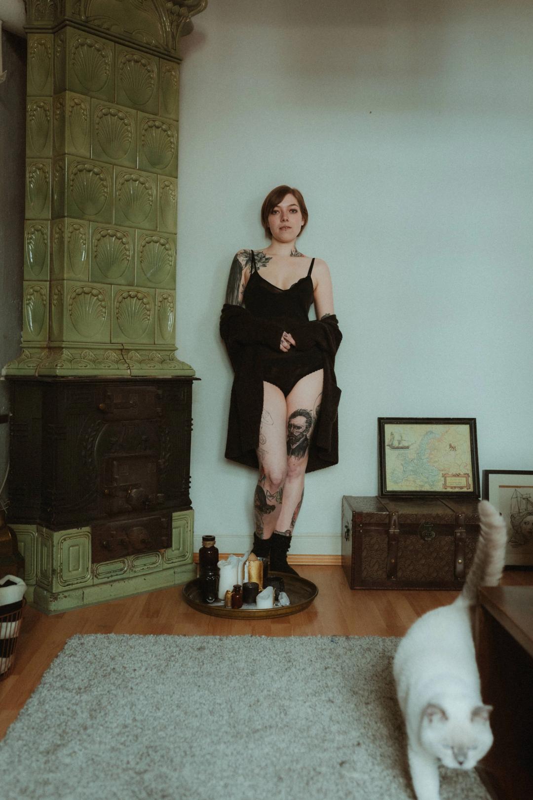 Anki stands in her living room with a white cat in the foreground.
