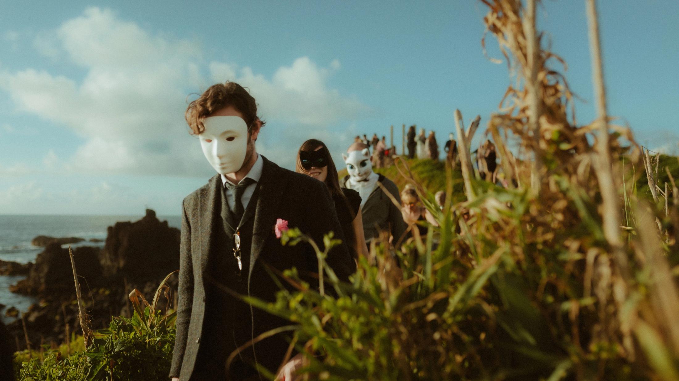 Masked participants walk down the coastal path in warm evening light.