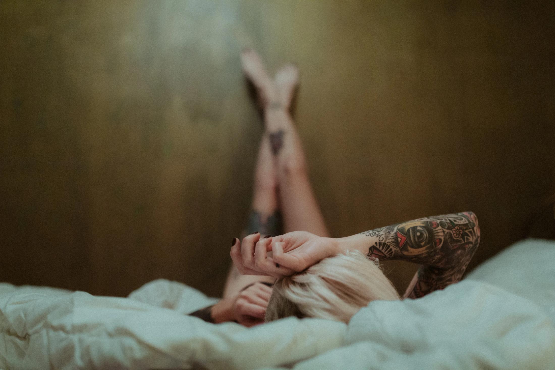 Tattooed woman resting quietly on a bed