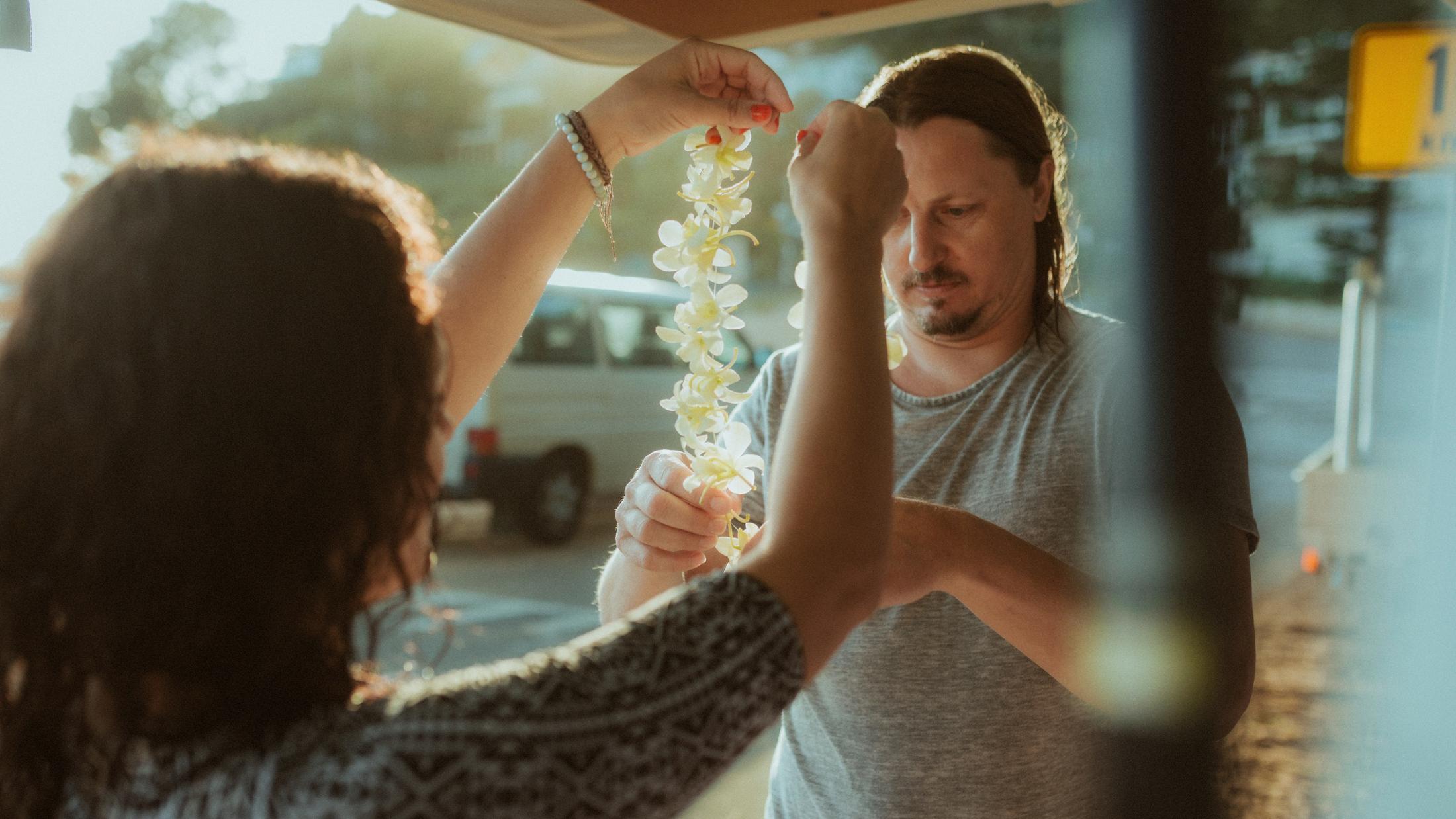 Roman helping Petra with a long white flower lei