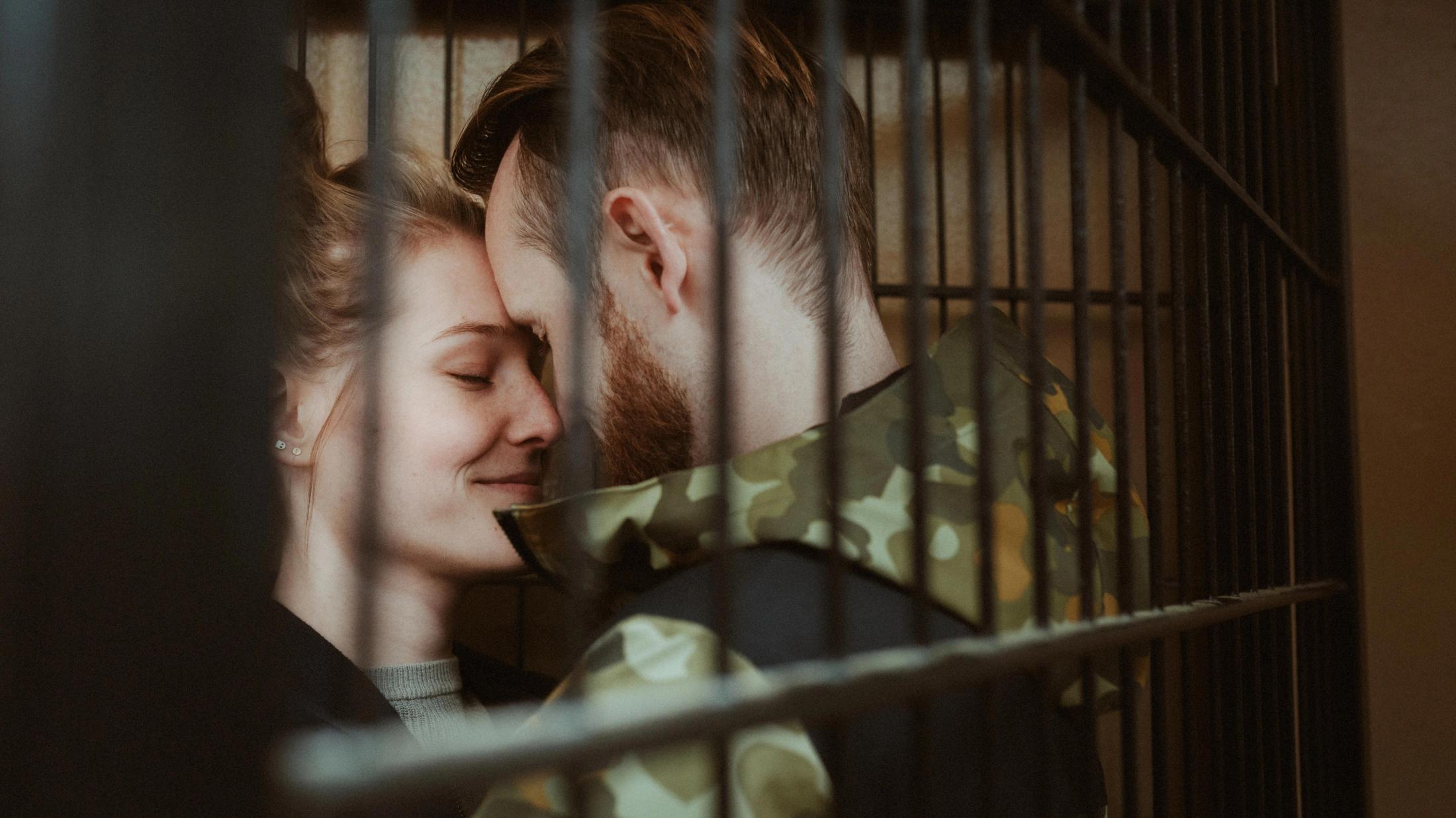 Caro and Bjørn touch behind a reflective pane of glass.