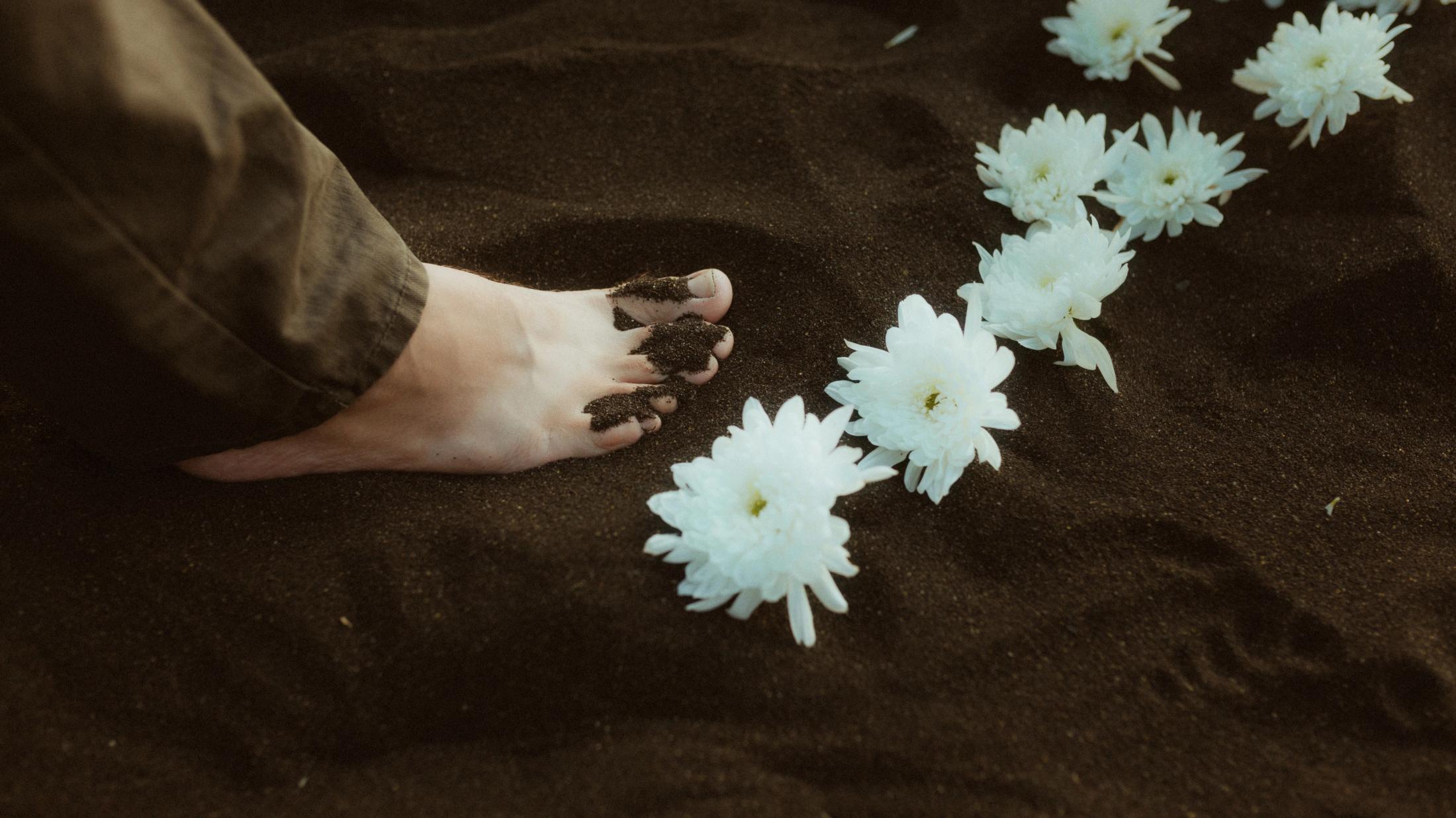 White flowers rest on black volcanic sand before the ceremony.