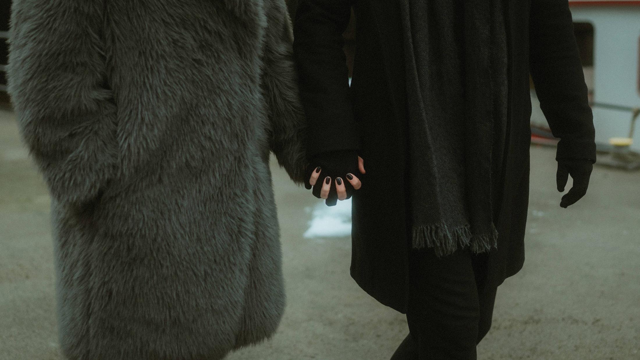 Lorelai's and Steffen's hands meet between their dark winter coats.