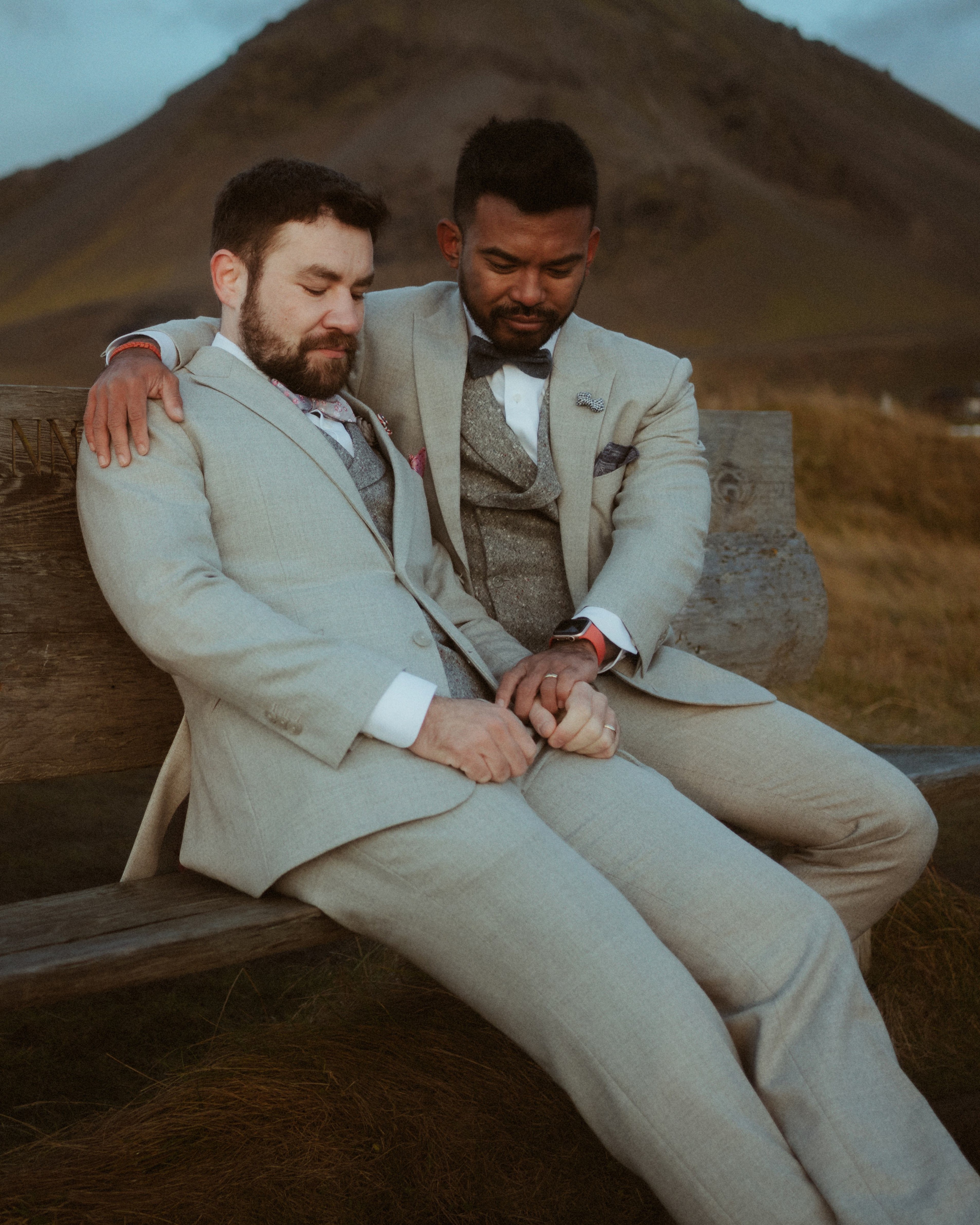Kris holds Ilya close as they sit together on a wooden bench.