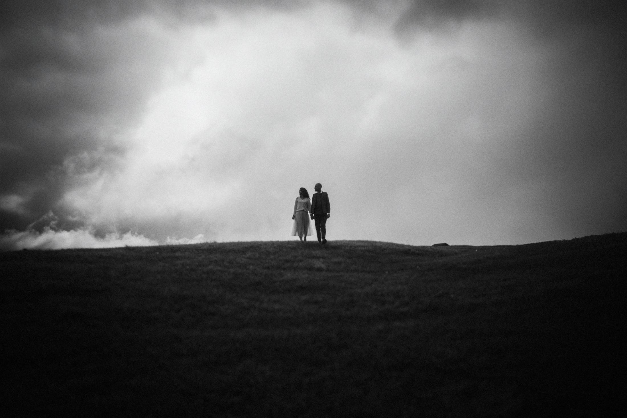 The couple appearing as small silhouettes beneath a large bank of cloud.