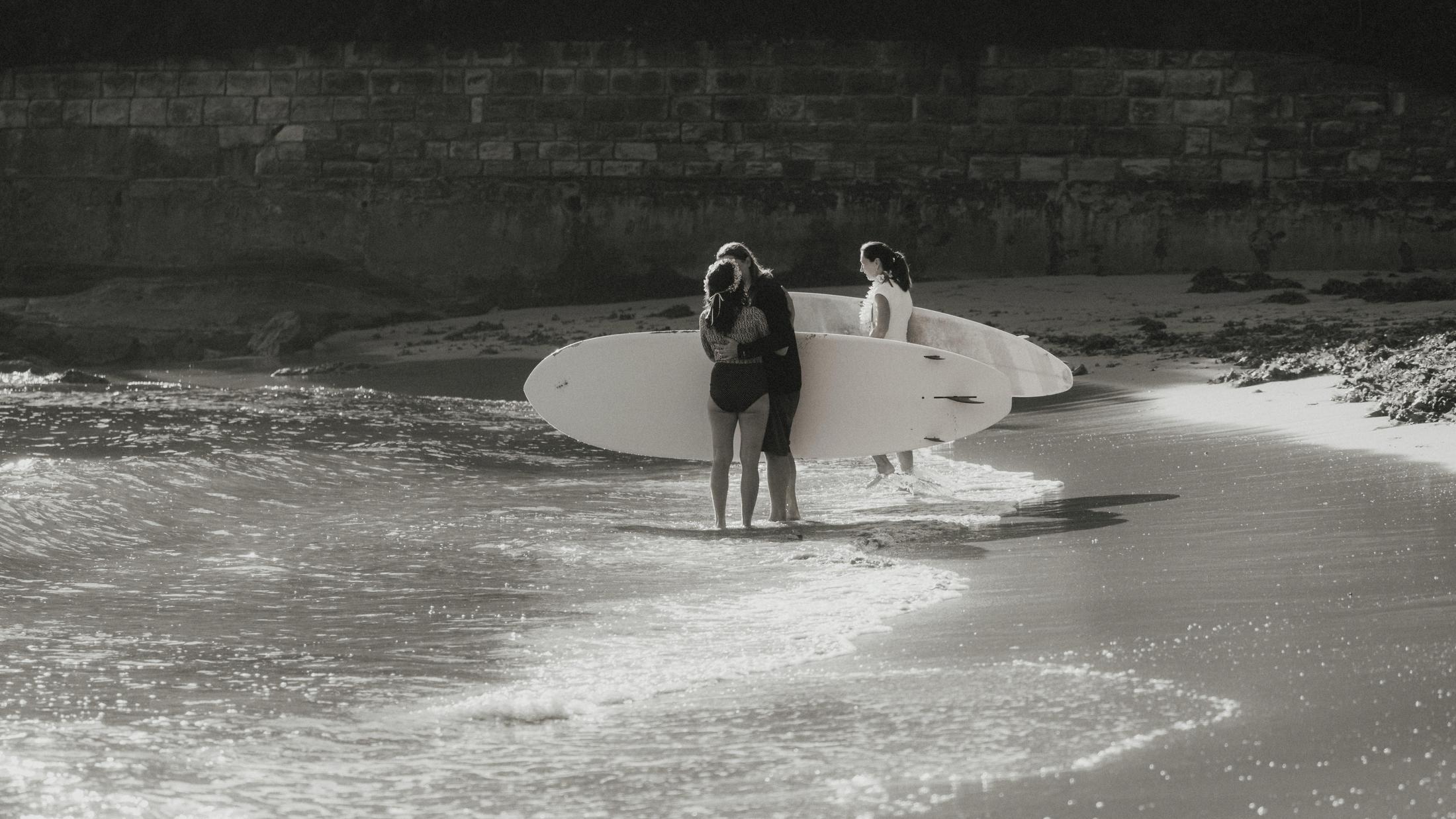 Black and white view of Petra and Roman entering the surf with their boards