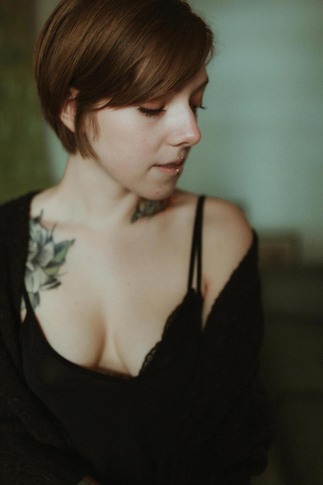 Anki looks down in a close portrait against a pale wall.