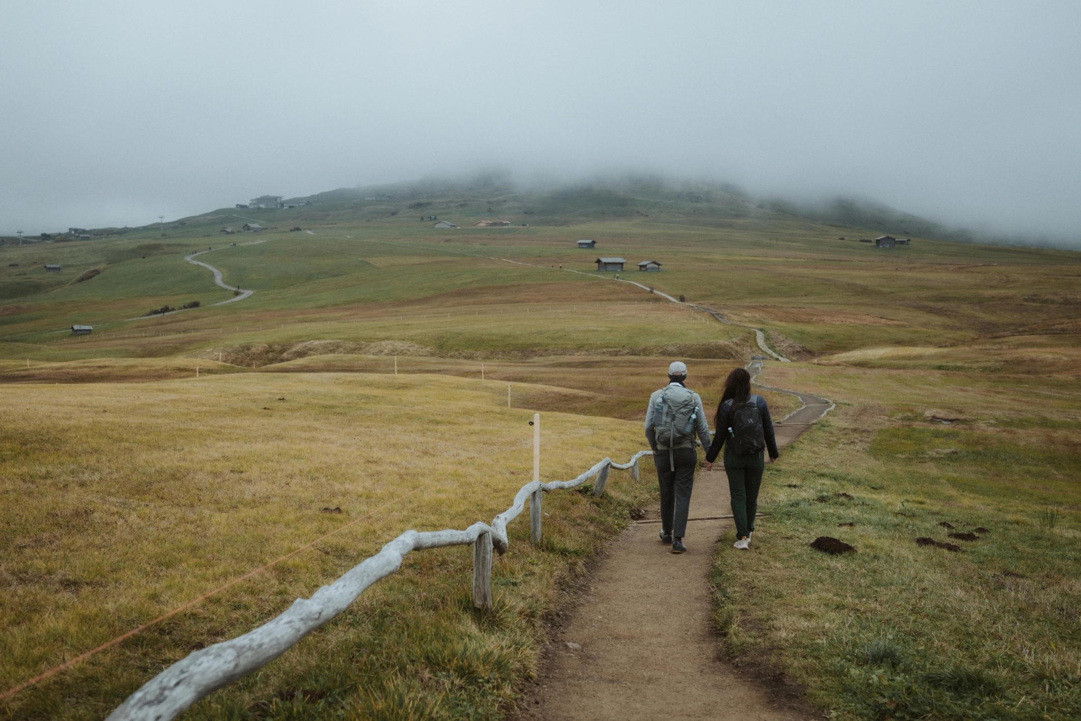 Jana and Steffen walking down an alpine path surrounded by fog.