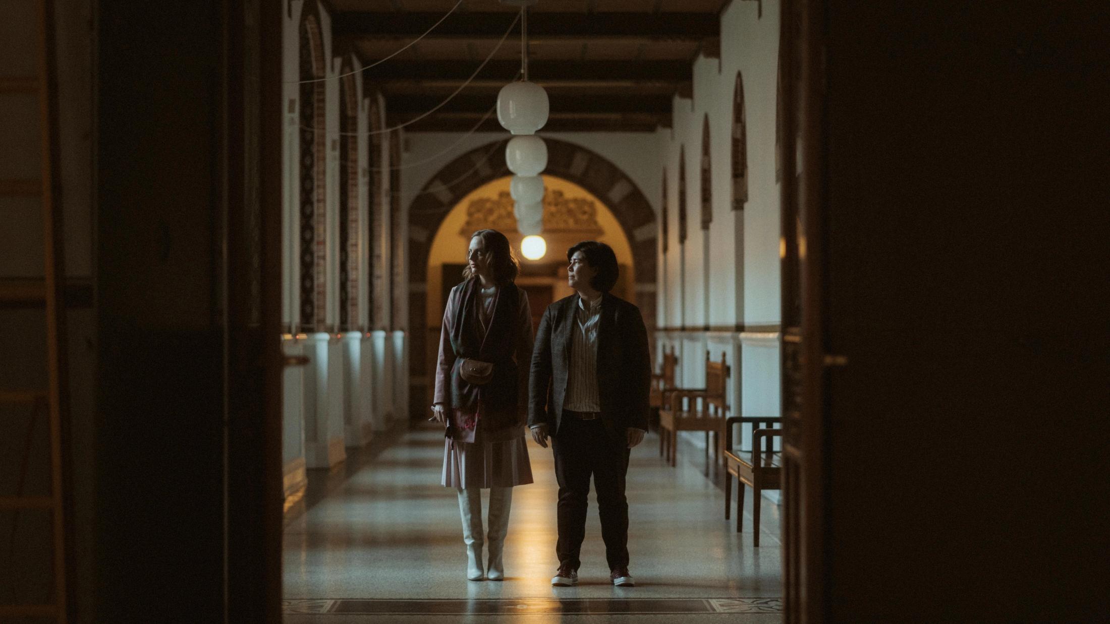 Ari and Pia standing small in a long City Hall corridor