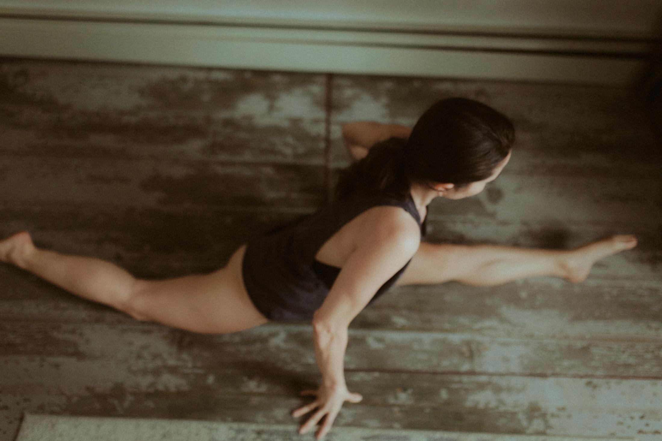 Maya moving through a low floor pose in the apartment.