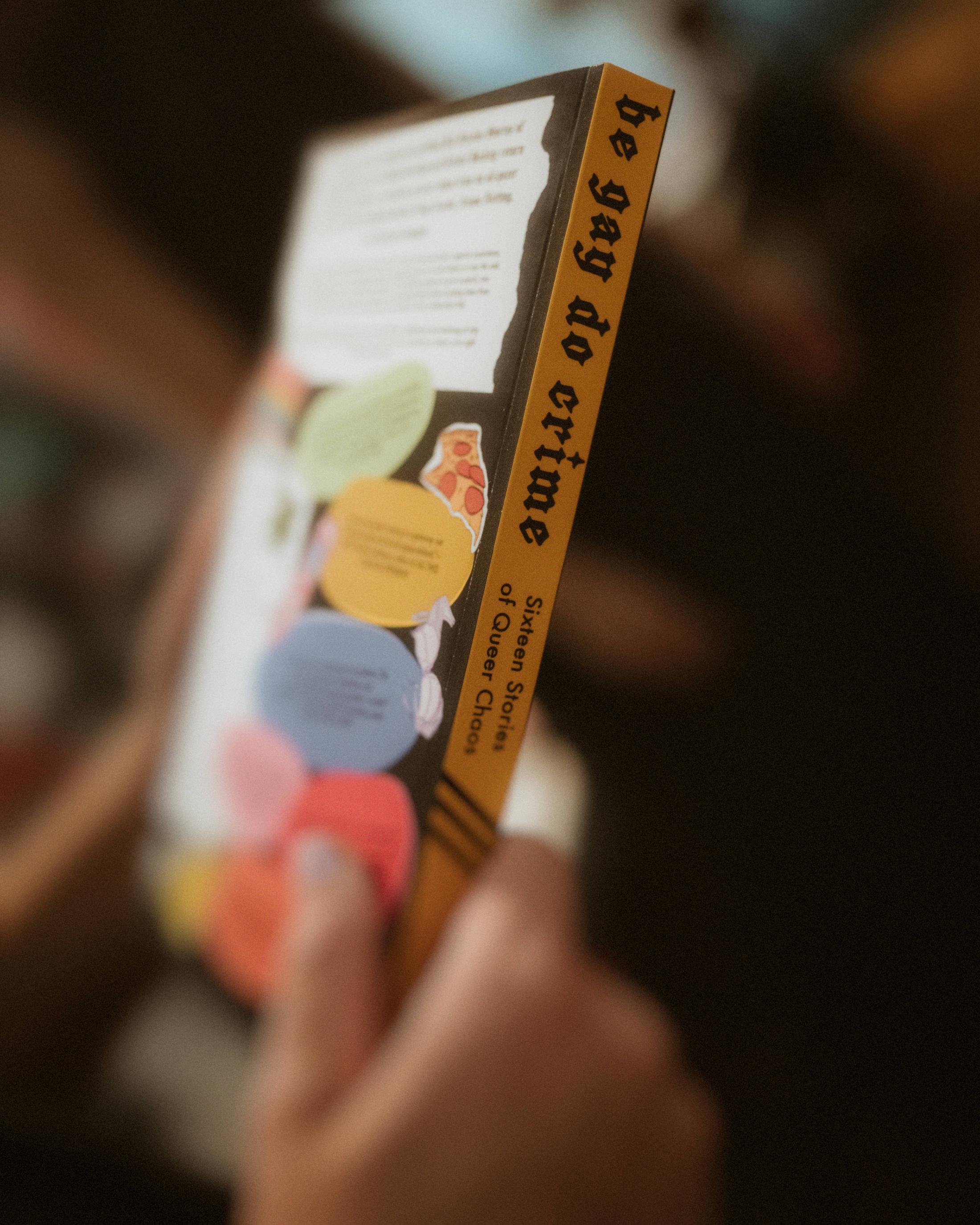 A hand holding a book filled with colorful page markers.