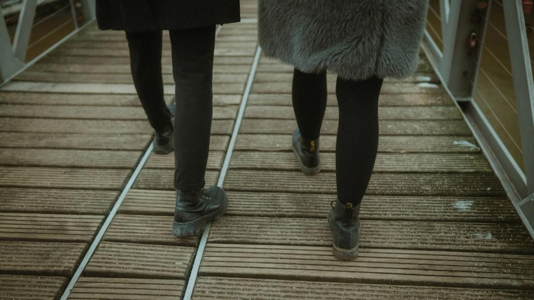 Rear view of Lorelai and Steffen walking side by side across the wooden bridge.