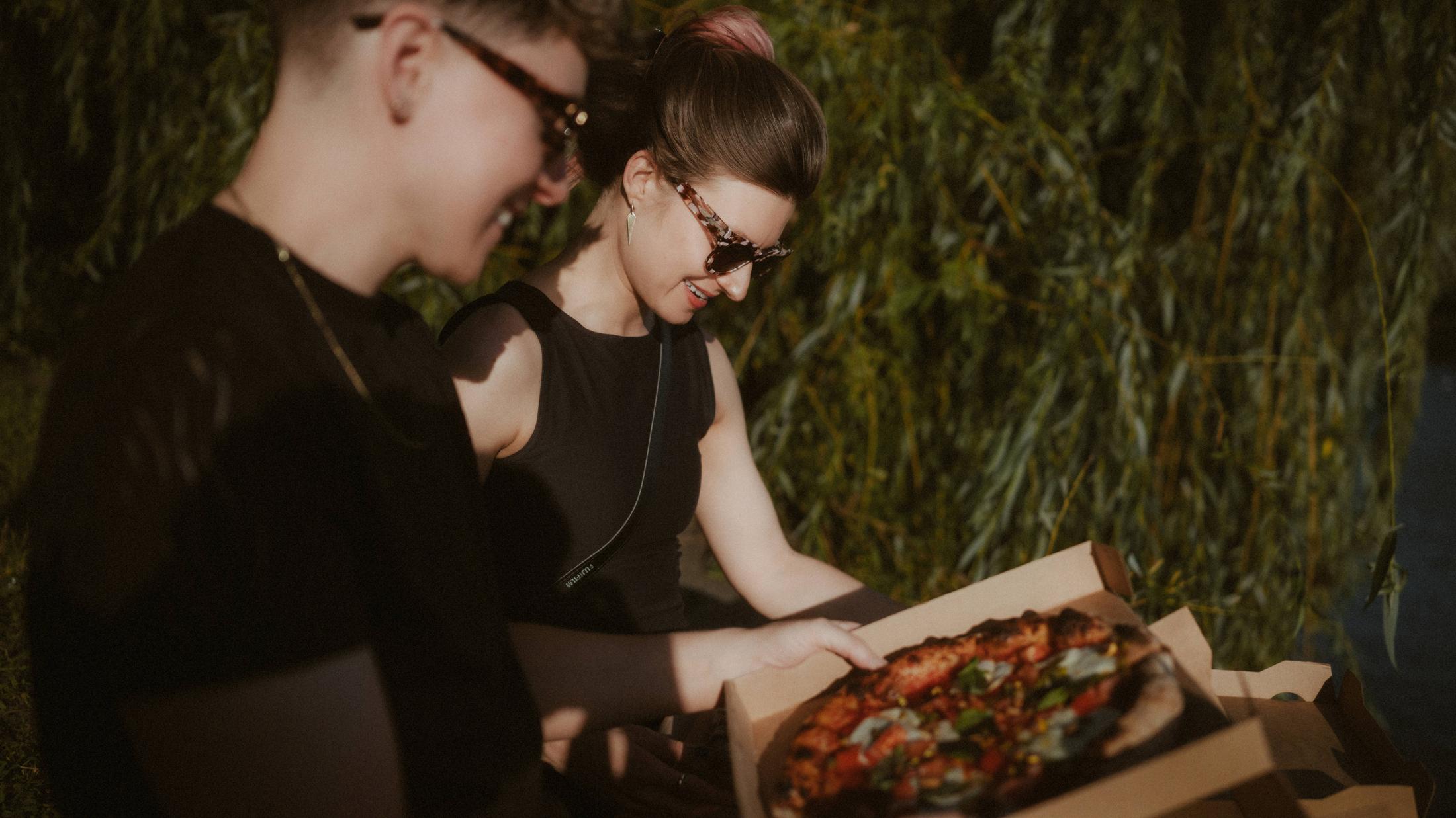 Noah and Michèle sitting together and eating pizza beside the Landwehrkanal.